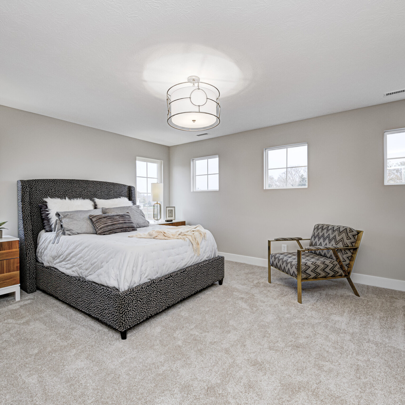 A bedroom with a bed, dresser and chair in a custom home built by Indianapolis Custom Homes.