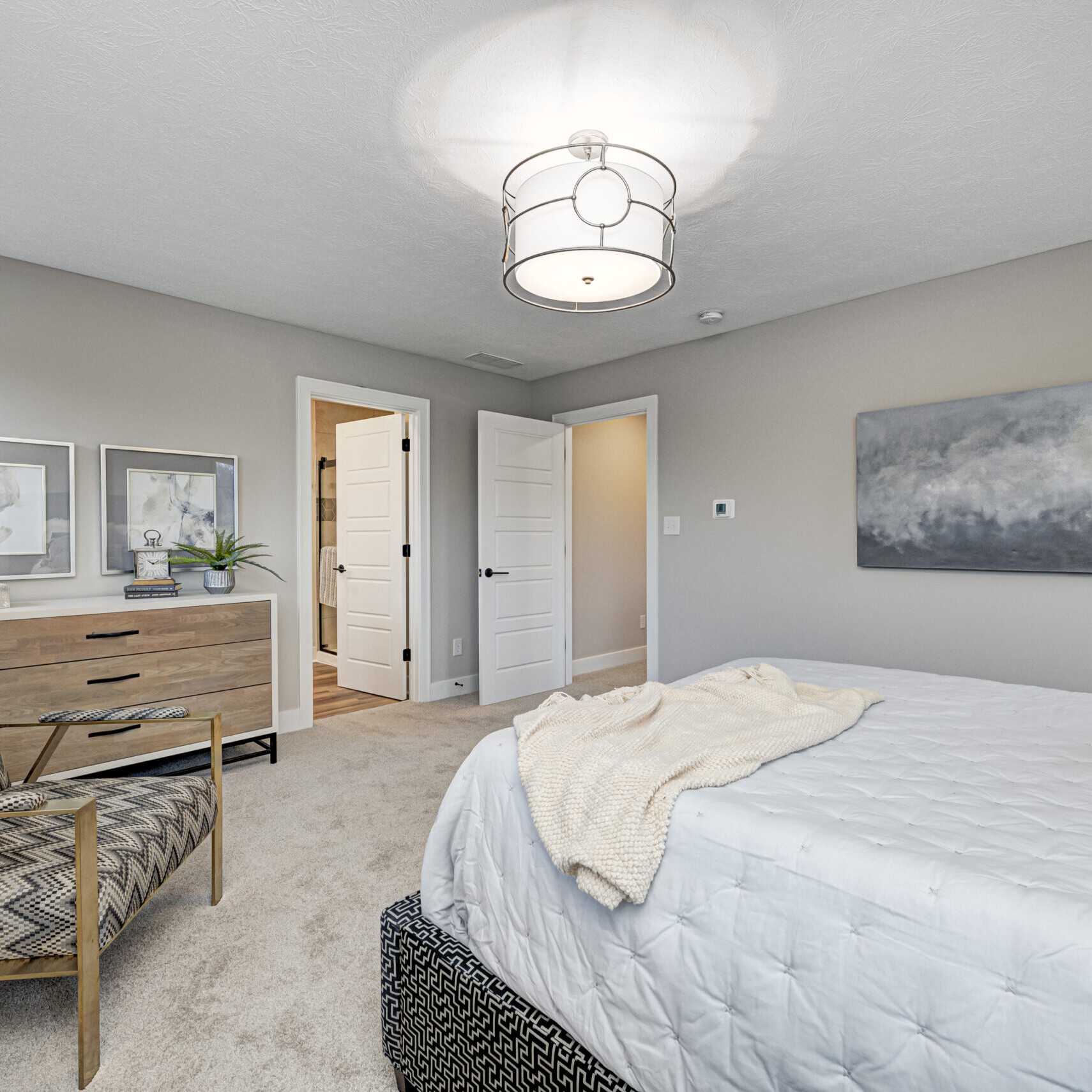 A bedroom with a bed, dresser and chair designed by a Custom Home Builder in Carmel Indiana.