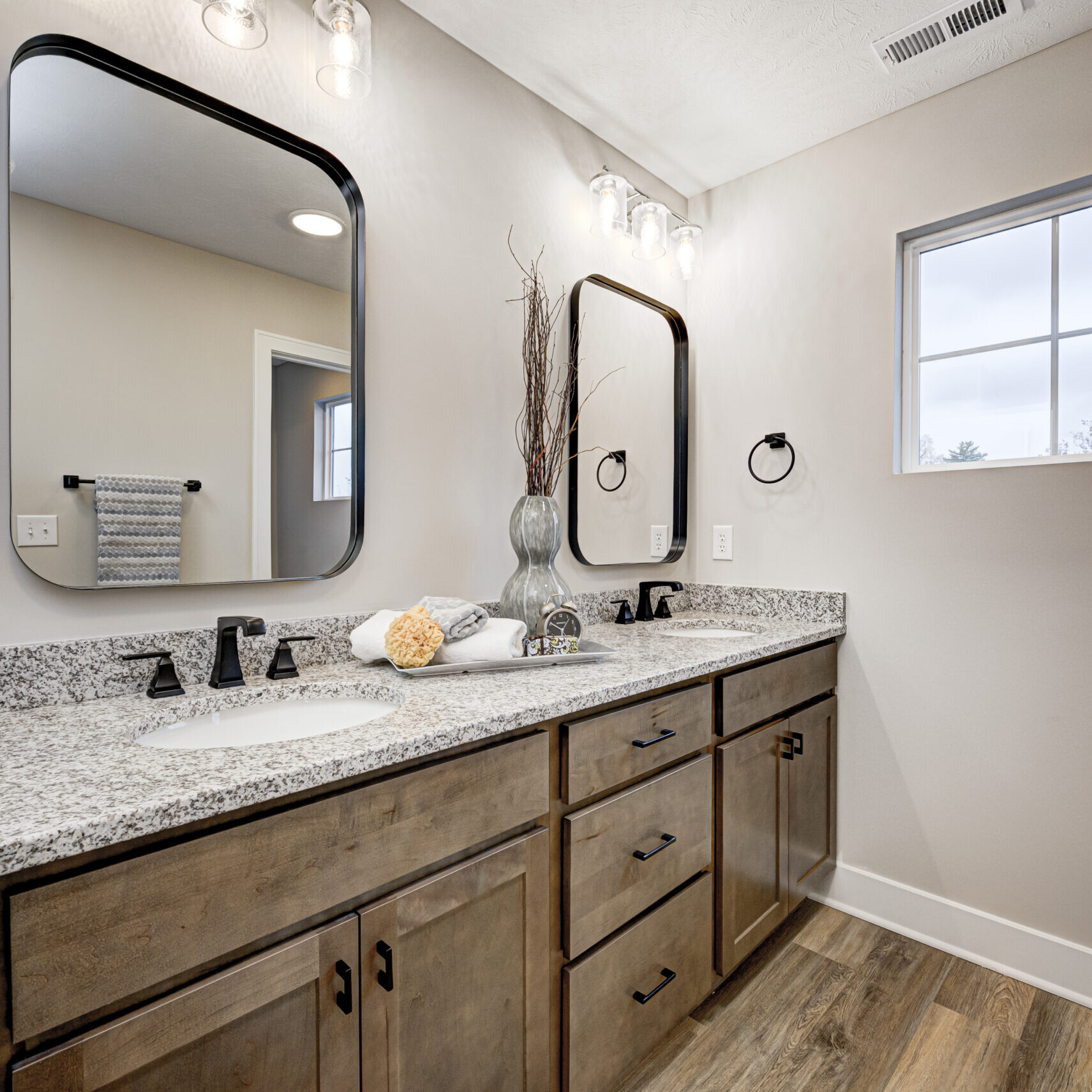 A bathroom with two sinks, a mirror, and custom home builder Carmel Indiana.