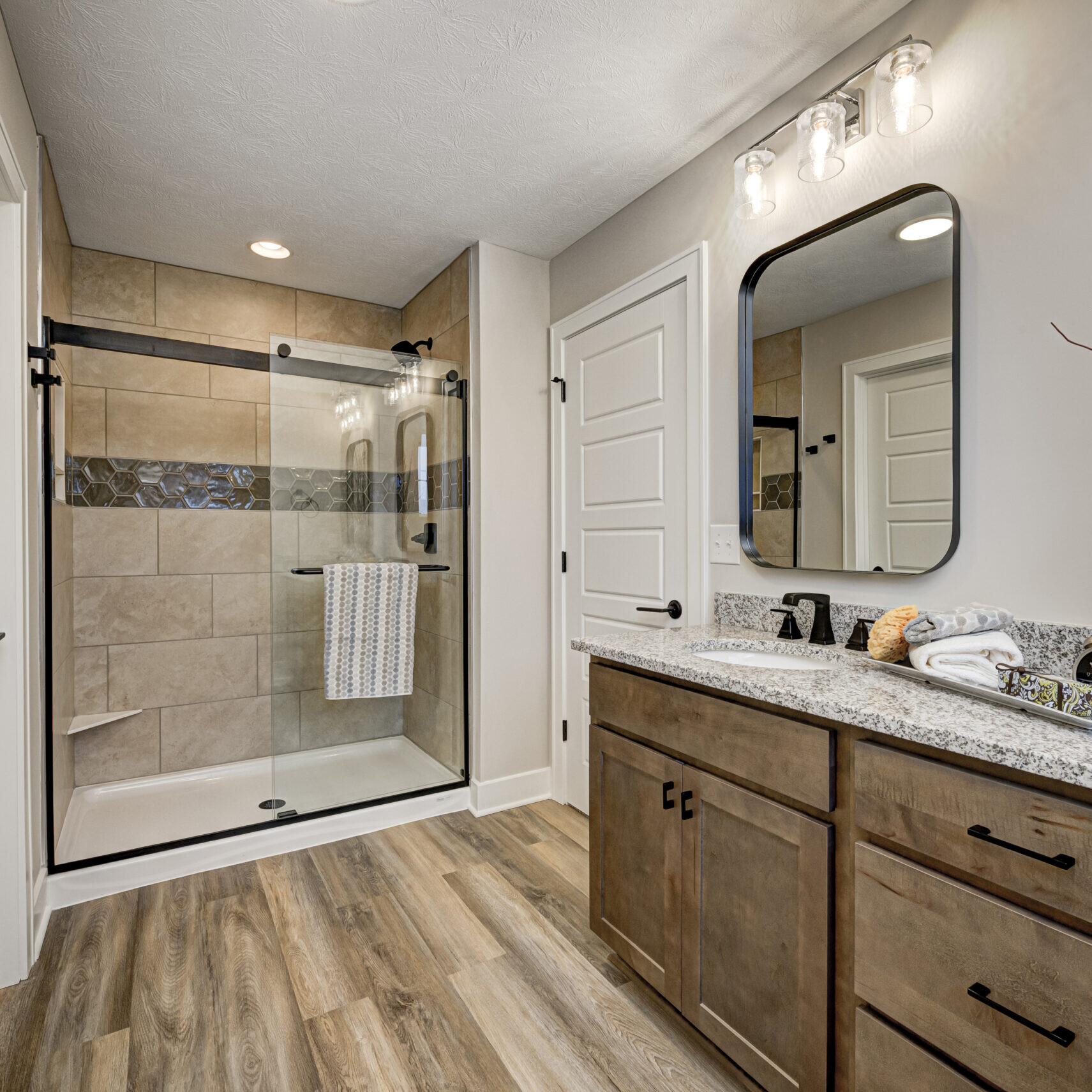 A custom bathroom featuring hardwood floors and a luxurious walk-in shower.