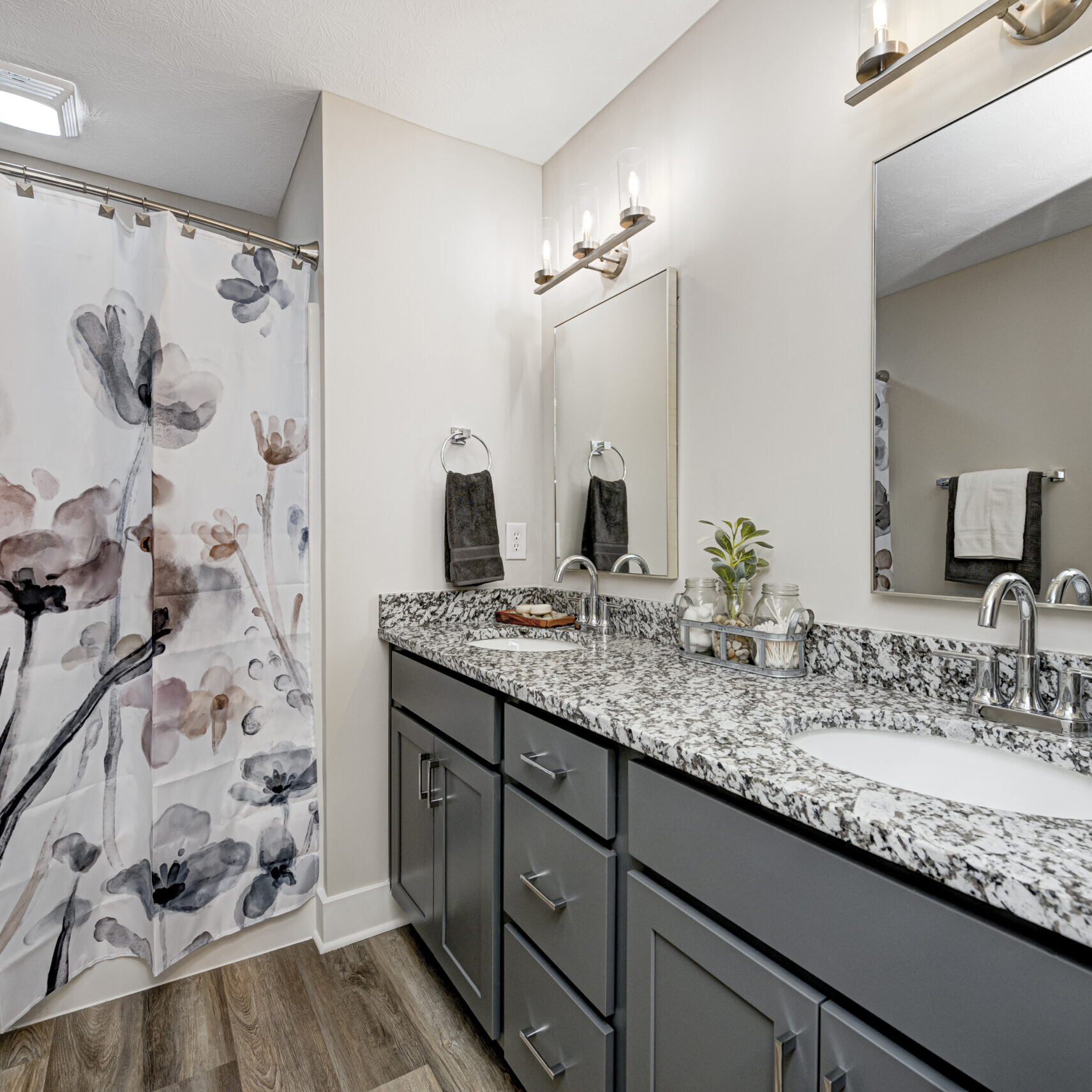 A bathroom with gray counter tops and a custom shower curtain.