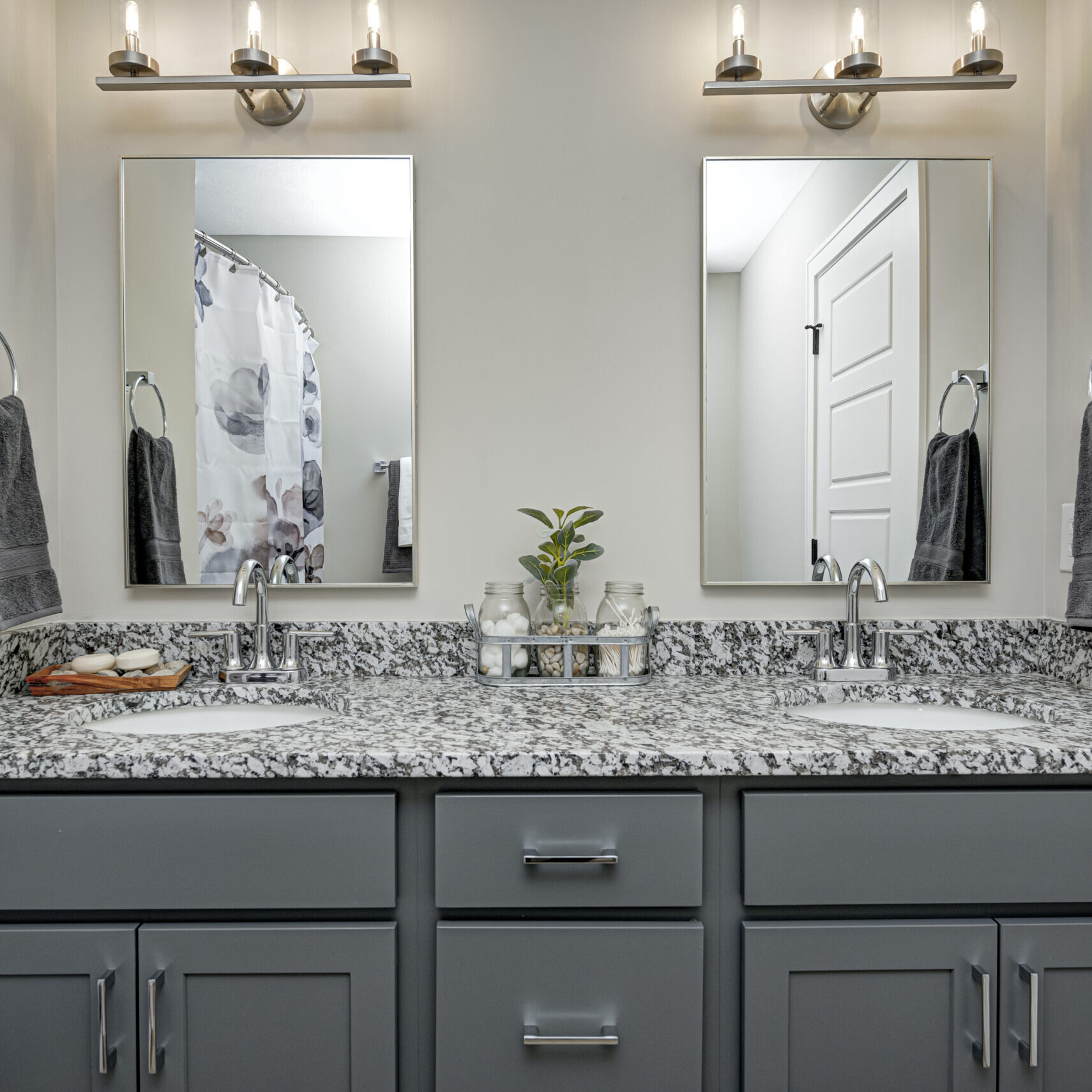 A bathroom with gray cabinets and granite counter tops, designed by a Custom Home Builder in Fishers Indiana.