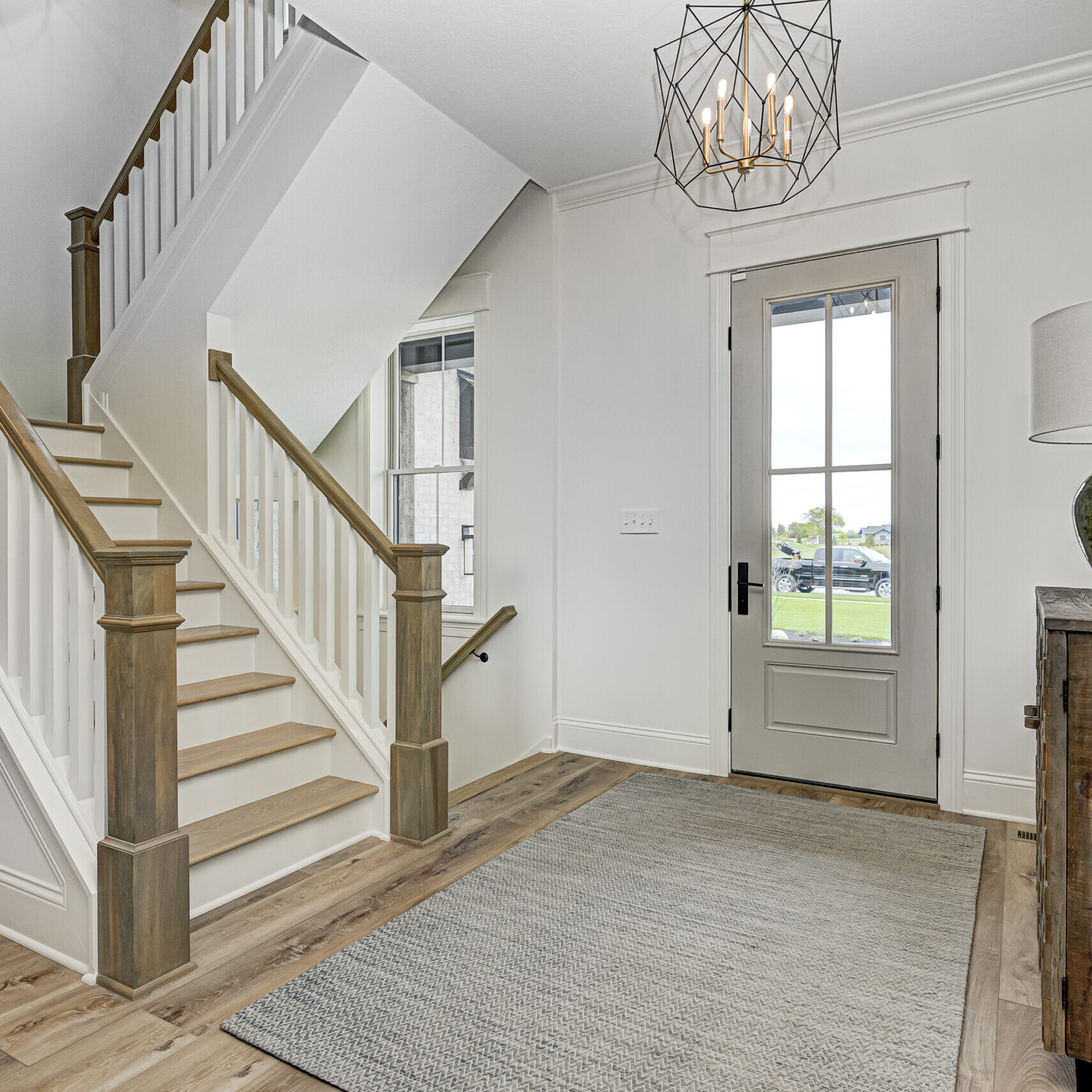 A hallway with hardwood floors and a staircase, designed by a Custom Home Builder in Indiana.