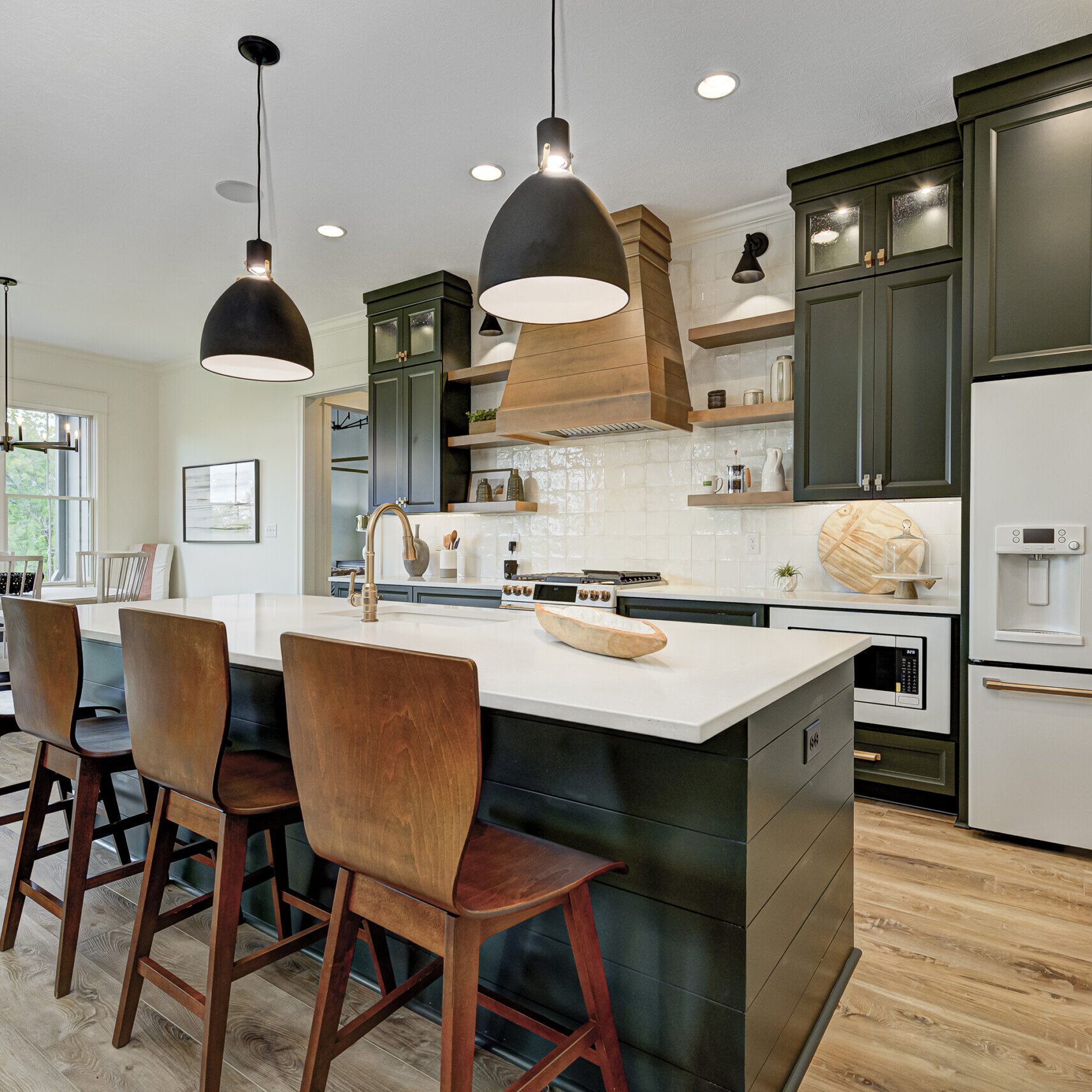 A kitchen with green cabinets and wood floors designed by a Custom Home Builder Fishers Indiana.