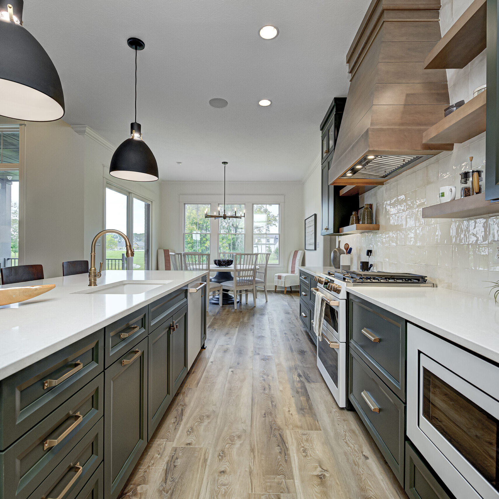 A kitchen with green cabinets and hardwood floors in a custom-built home.