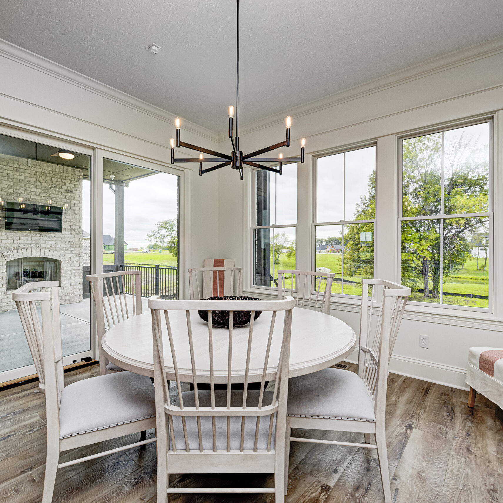 A dining room with hardwood floors and a sliding glass door, designed by a Custom Home Builder in Carmel Indiana.