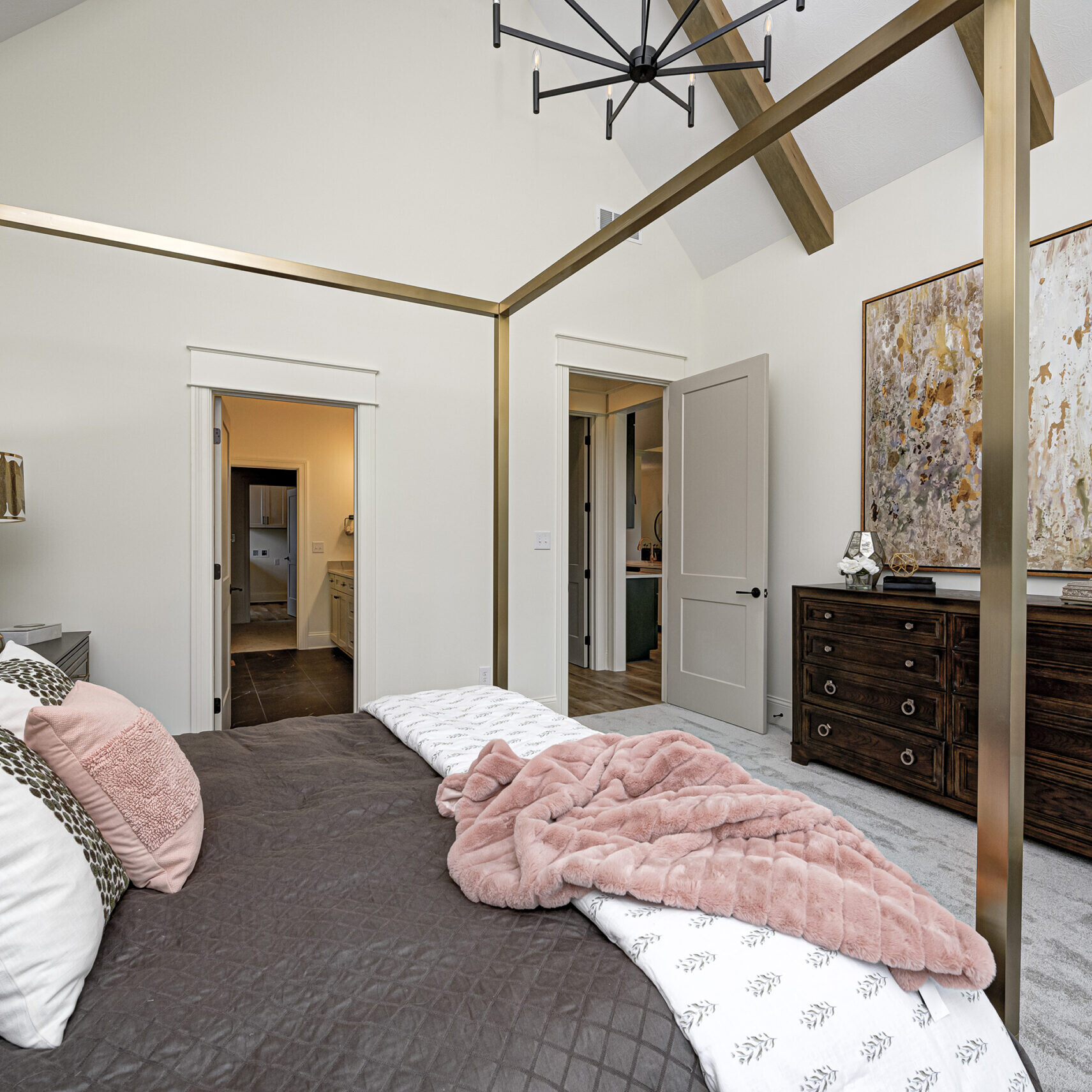A luxurious bedroom adorned with a four poster bed and an elegant chandelier in a custom-built home.