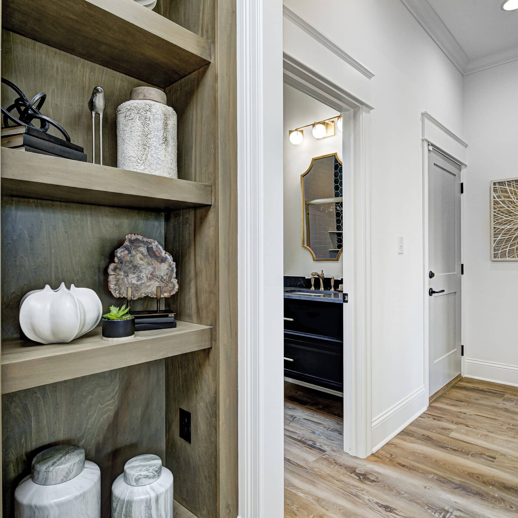 In the Indianapolis Custom Homes, a pristine hallway showcases a beautifully crafted wooden shelf adorned with an exquisite vase.