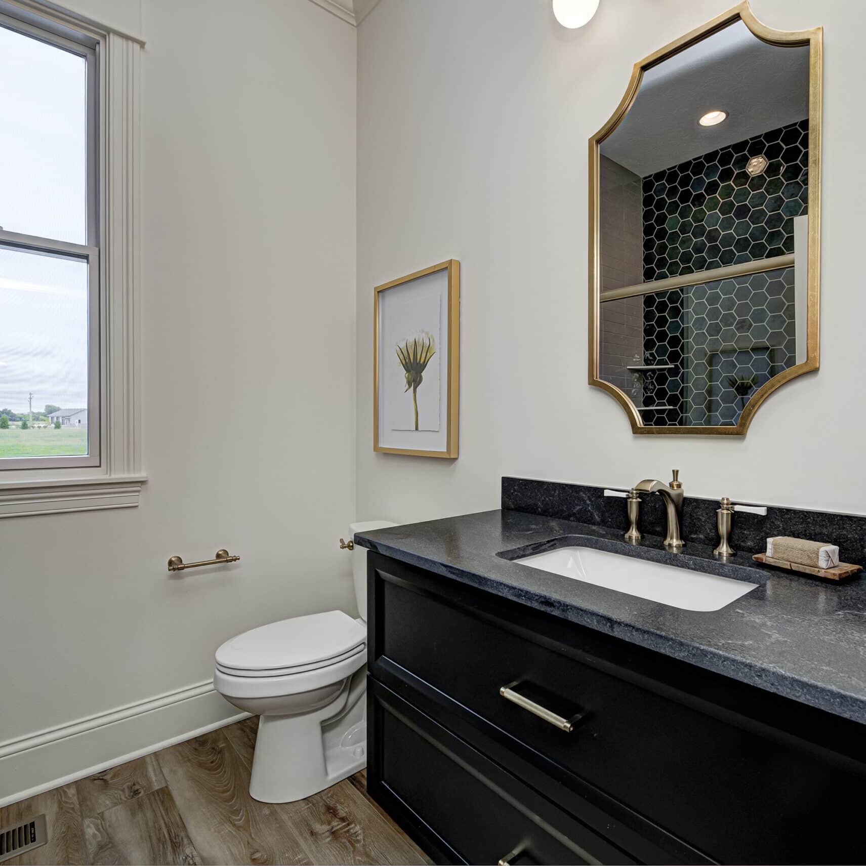 A bathroom with black countertops and a window, designed by Indianapolis Custom Homes.