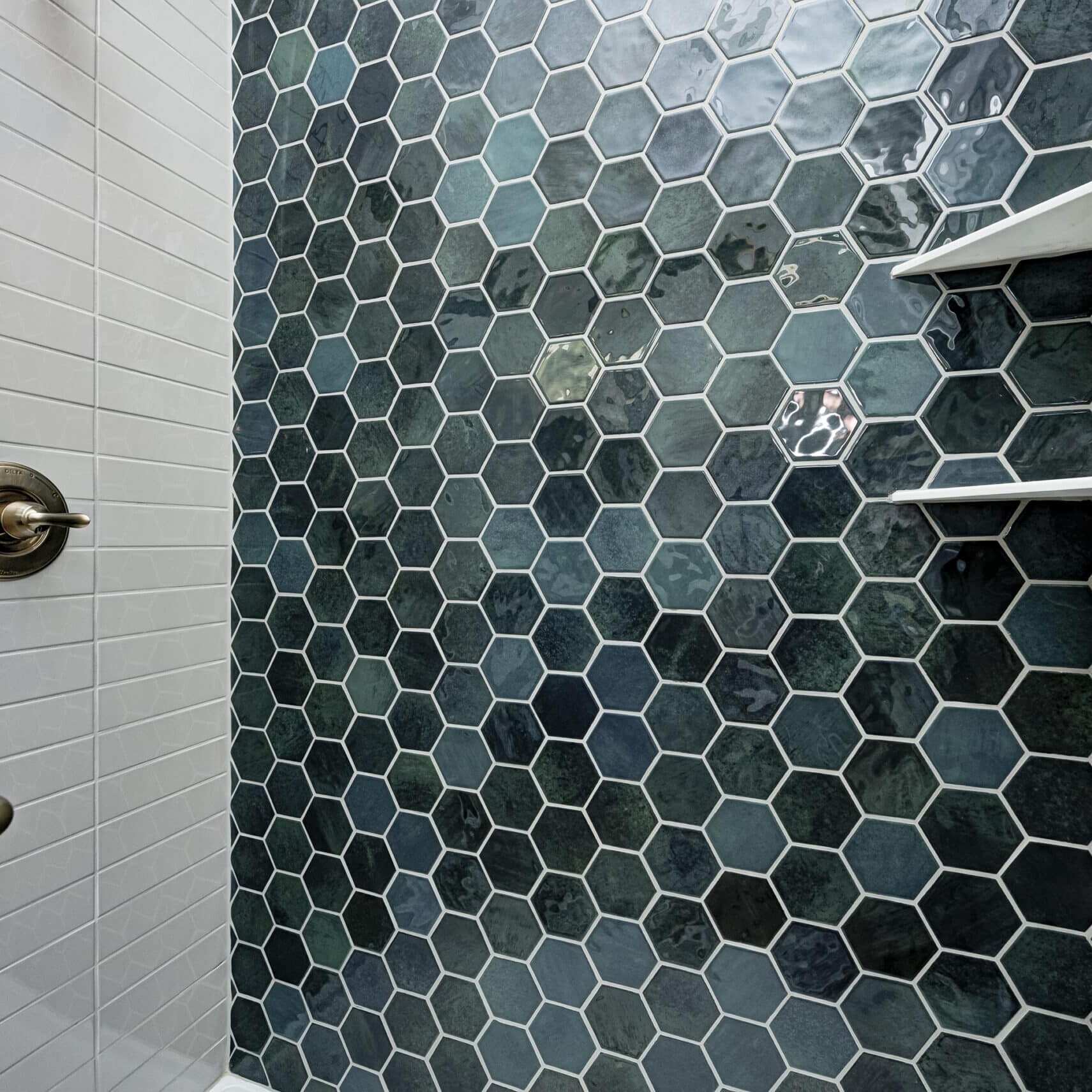 A blue tiled shower with a glass shelf in a custom home.