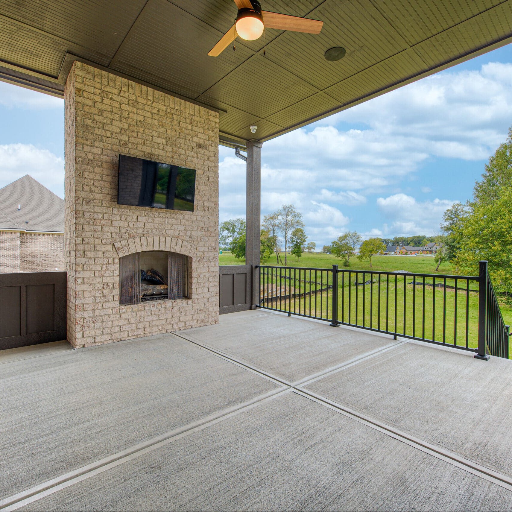 A covered patio with a fireplace and TV, designed by a skilled Custom Home Builder Carmel Indiana.