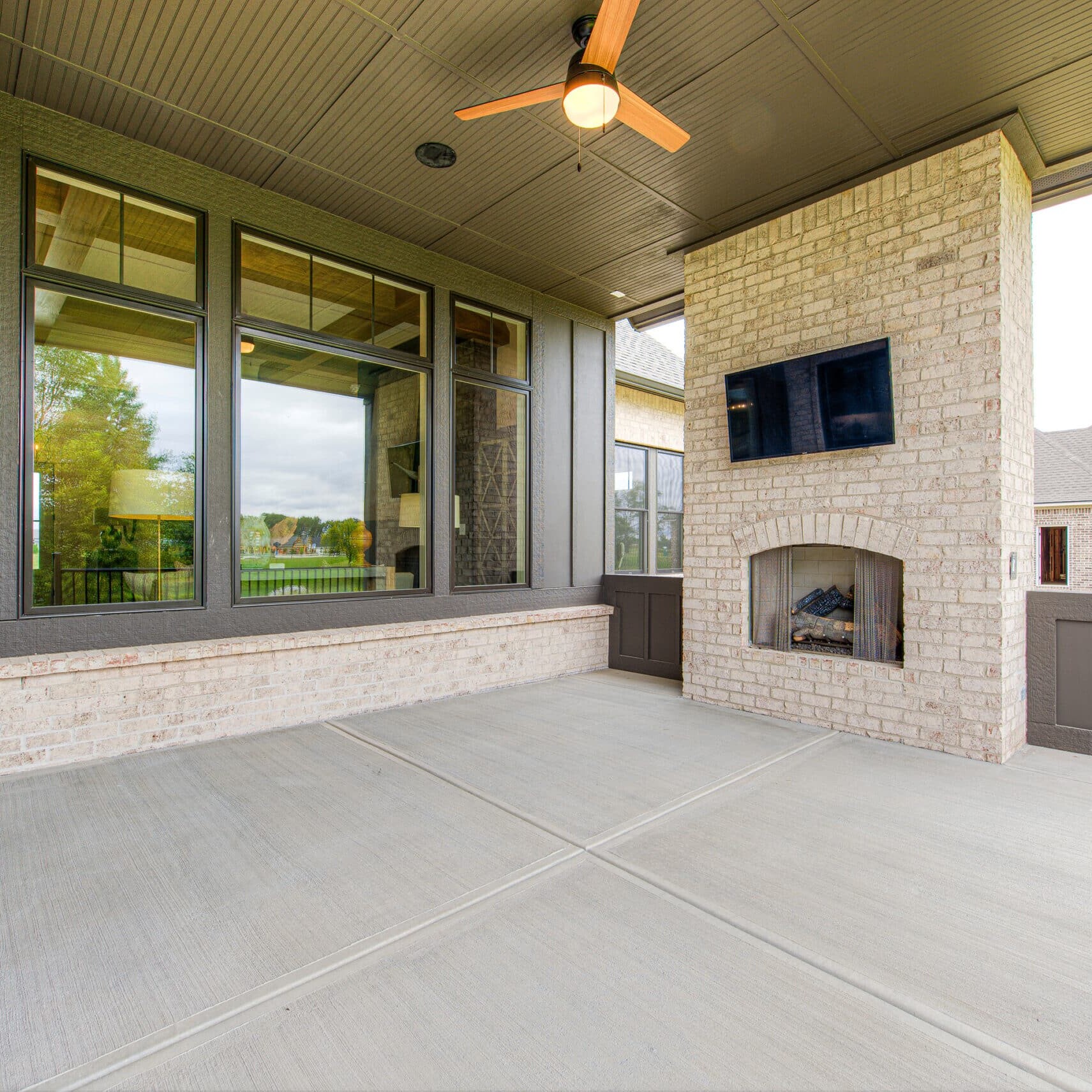 A luxurious outdoor space on a brick-covered patio, featuring a cozy fireplace and entertainment with a TV.