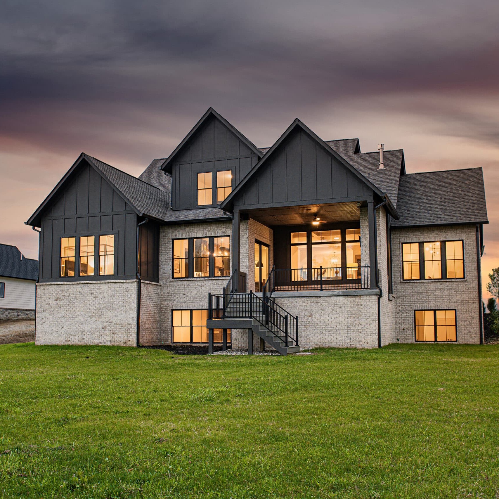 A large custom home with a sprawling lawn and a stunning sunset backdrop in Westfield, Indiana.