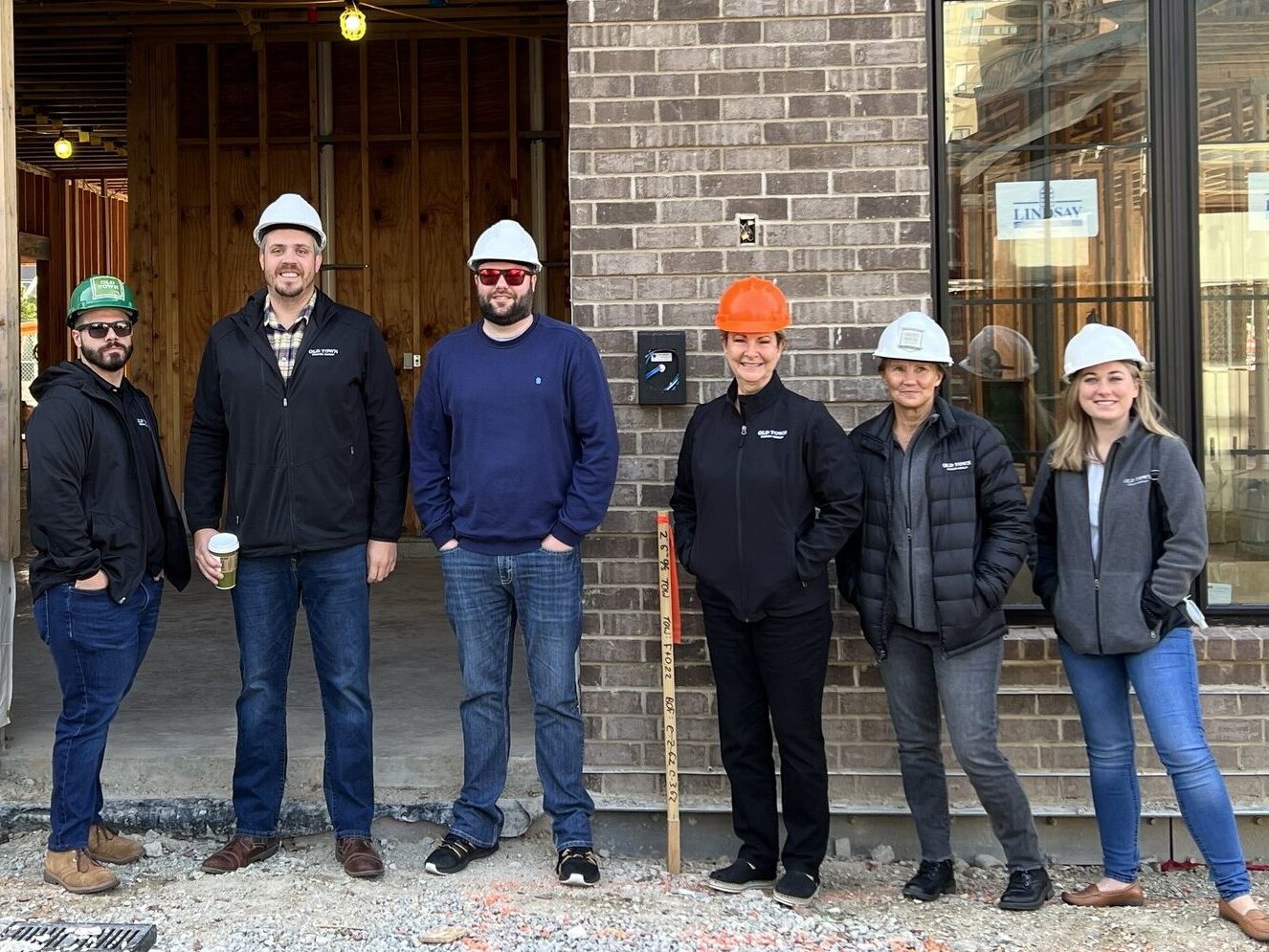 A group of people in hard hats standing in front of a building, showcasing their expertise in constructing custom homes.