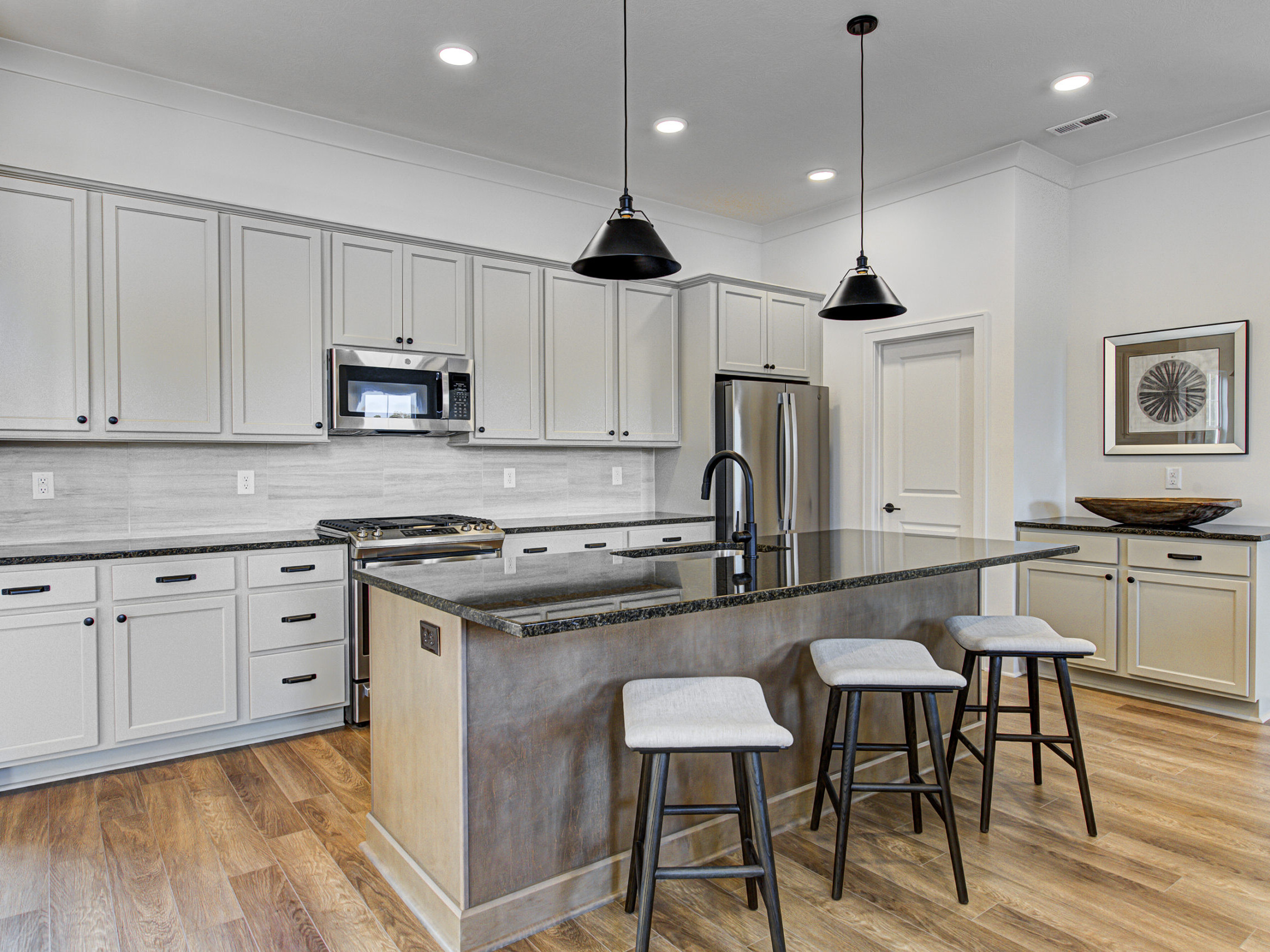 A kitchen with a center island and stools designed by a custom home builder in Carmel Indiana.