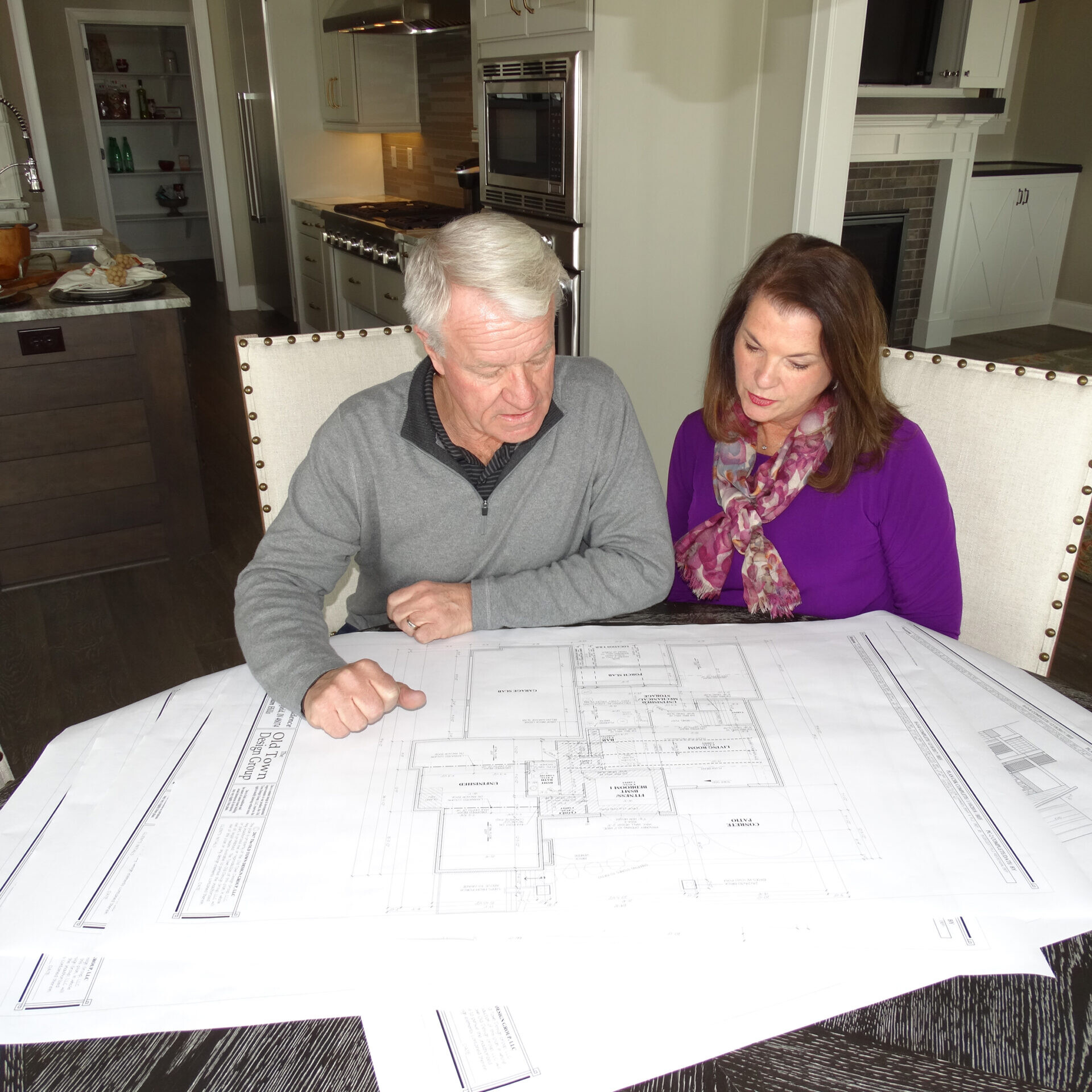 A couple sits at a table looking at blueprints for their new custom home.