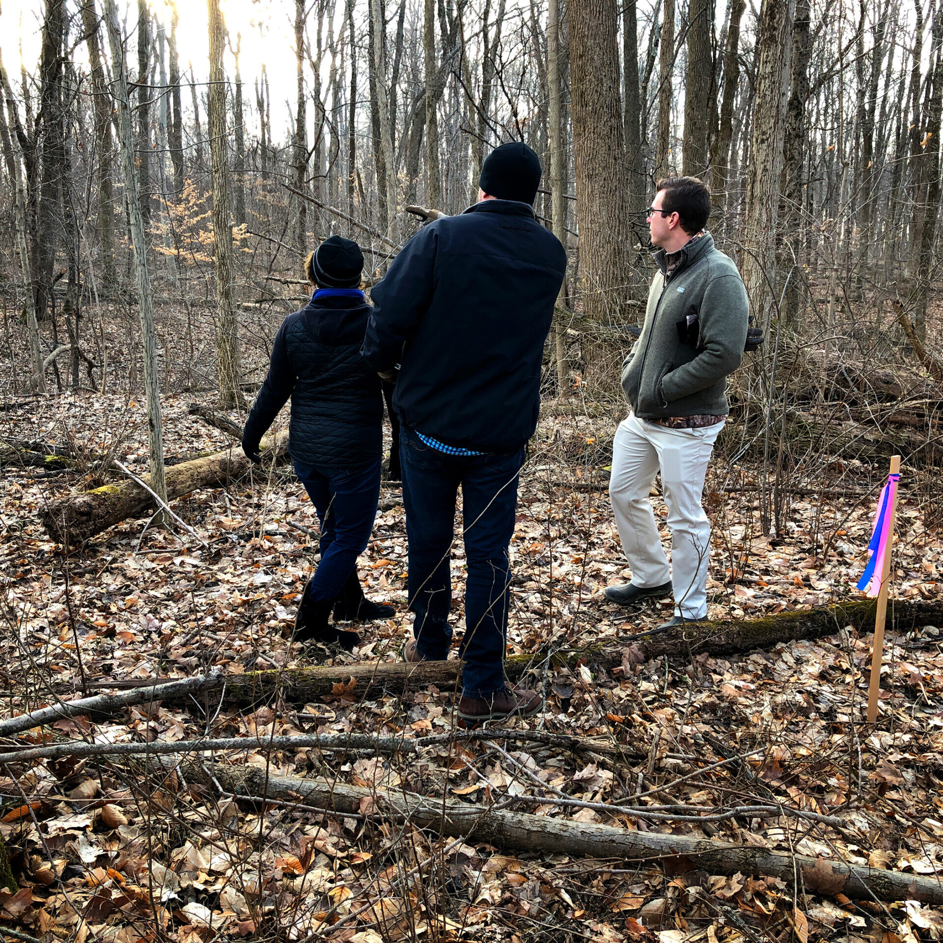 Three people standing in a wooded area near a custom home builder in Fishers, Indiana.