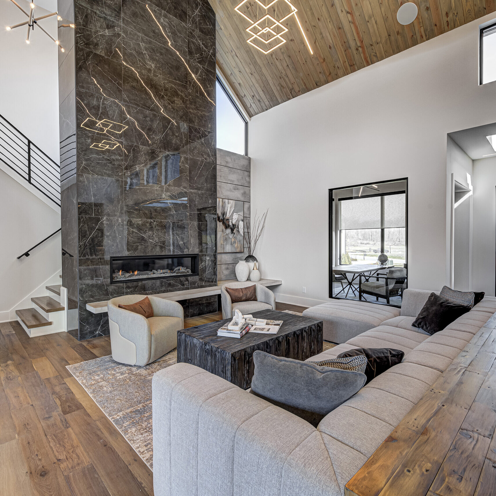 A modern living room with wood ceilings and a staircase.