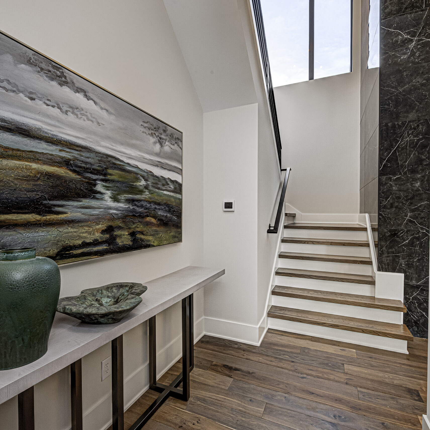 A hallway with hardwood floors and a painting on the wall.