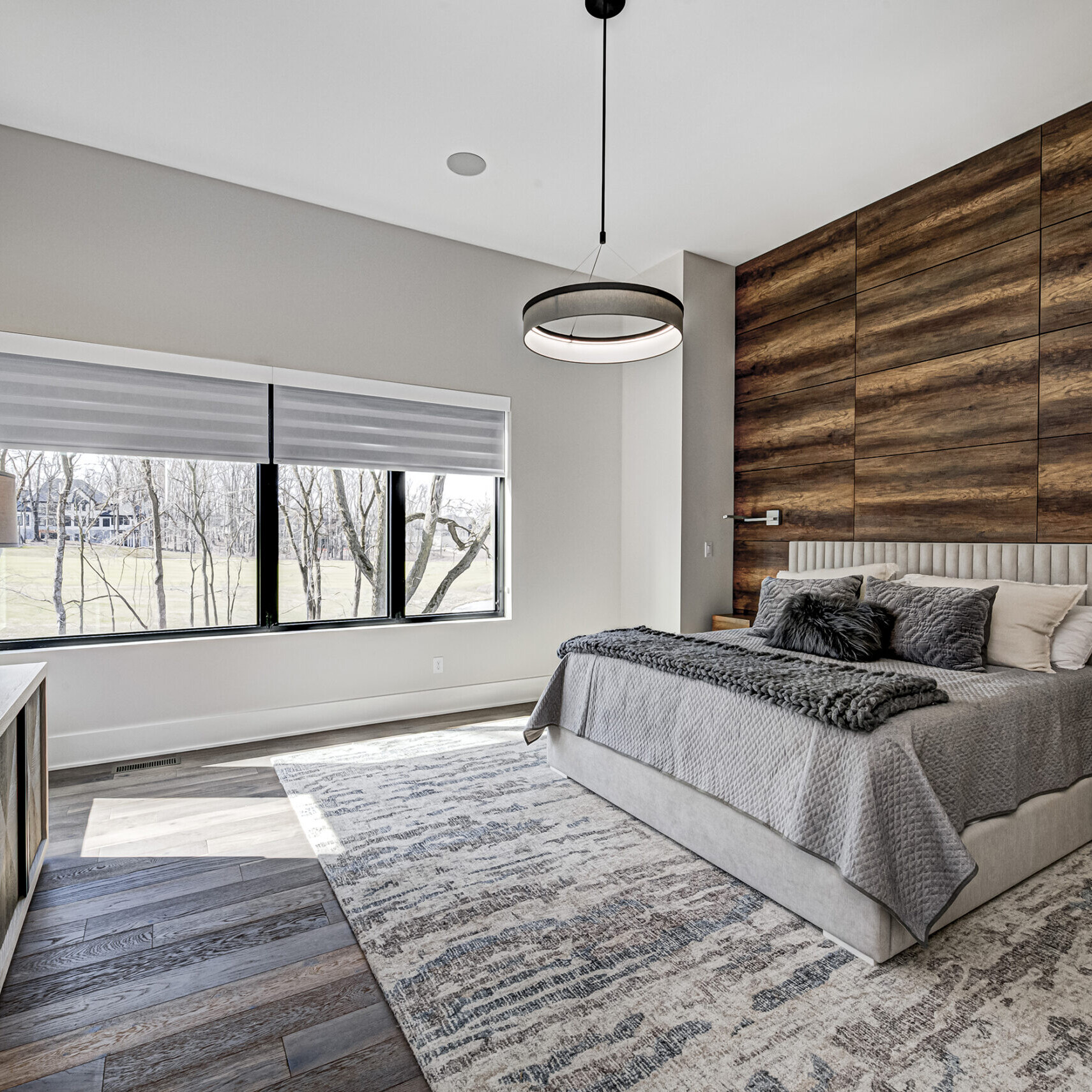 A modern bedroom with wood paneling and a bed.