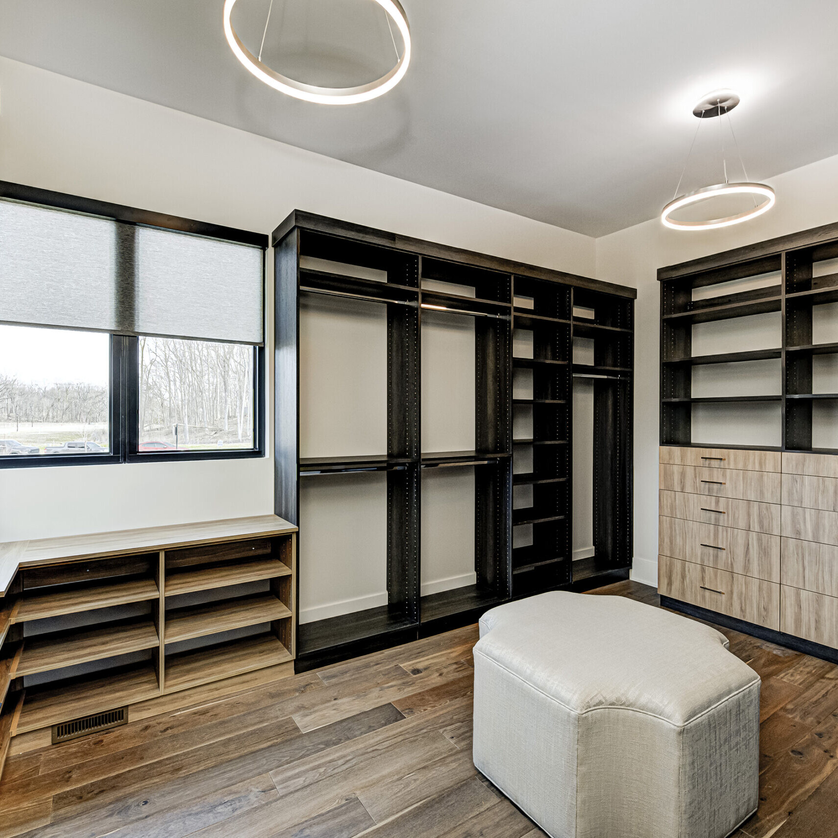 A walk in closet with shelves and a stool.