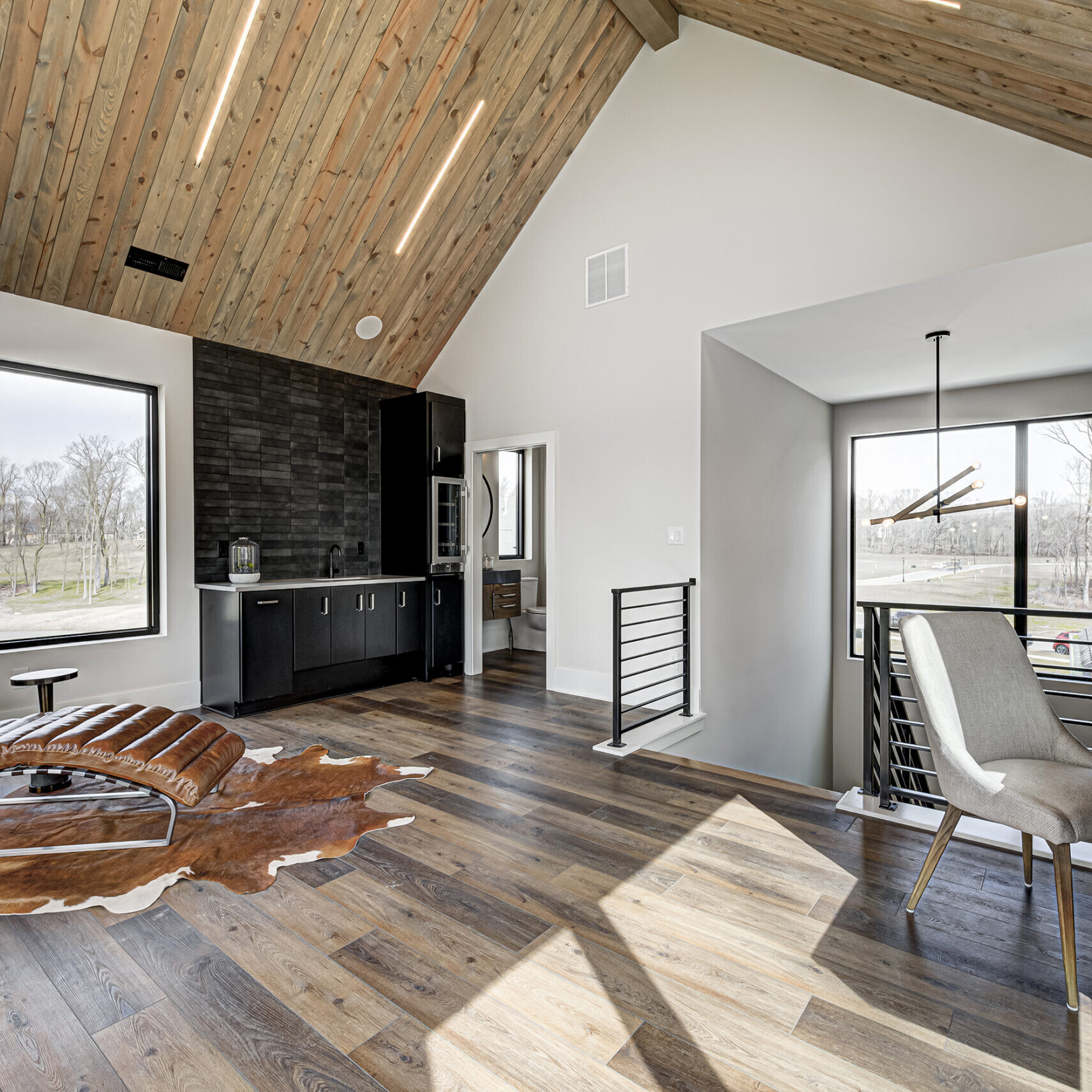 A modern living room with wood ceilings and a leather chair.