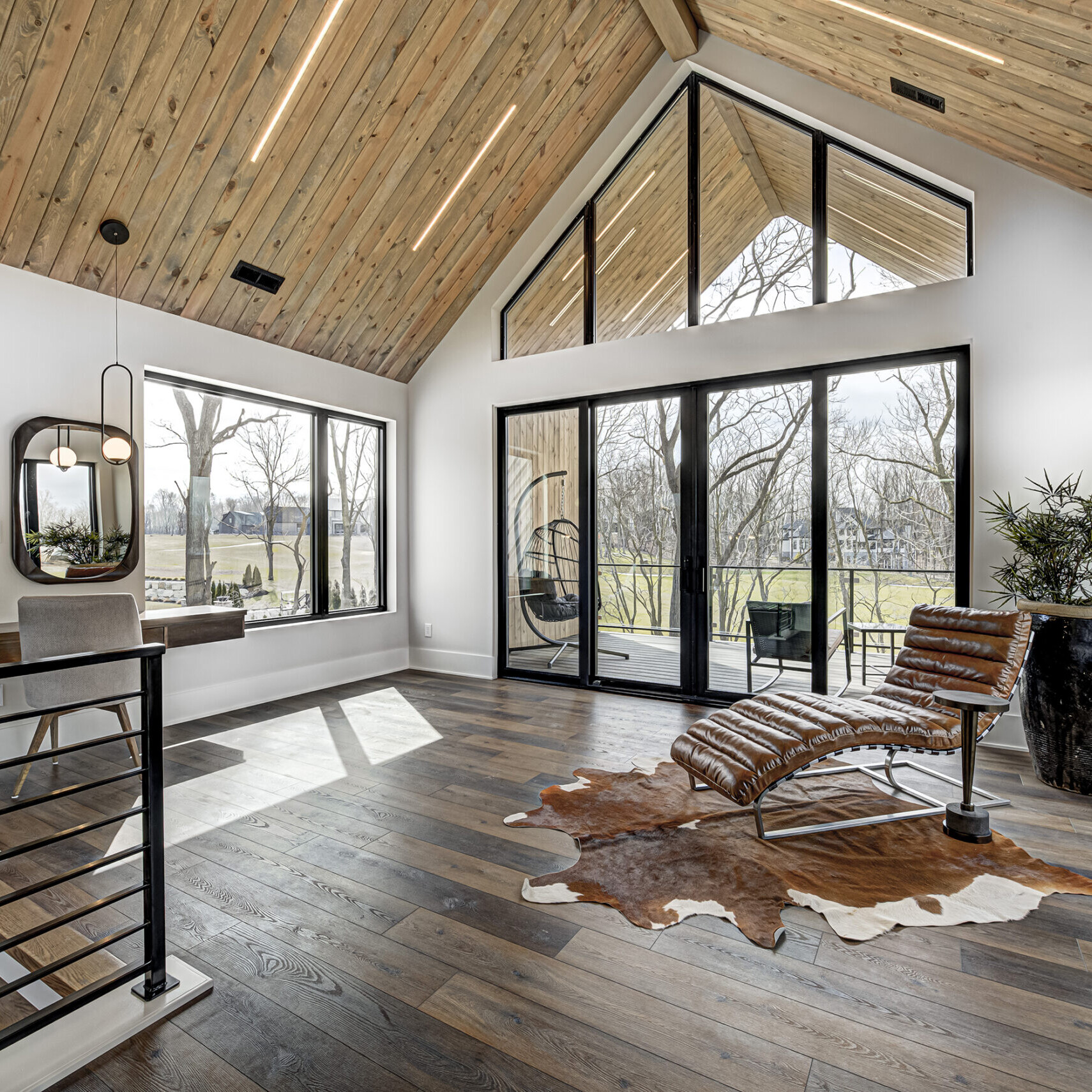 A modern living room with wood ceilings and a cowhide rug.