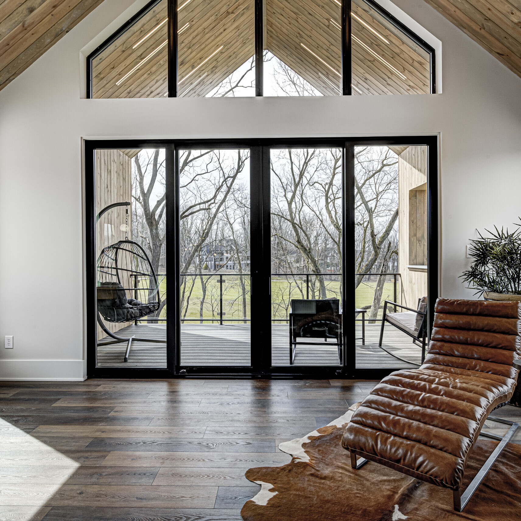 A living room with large windows and a leather chair.