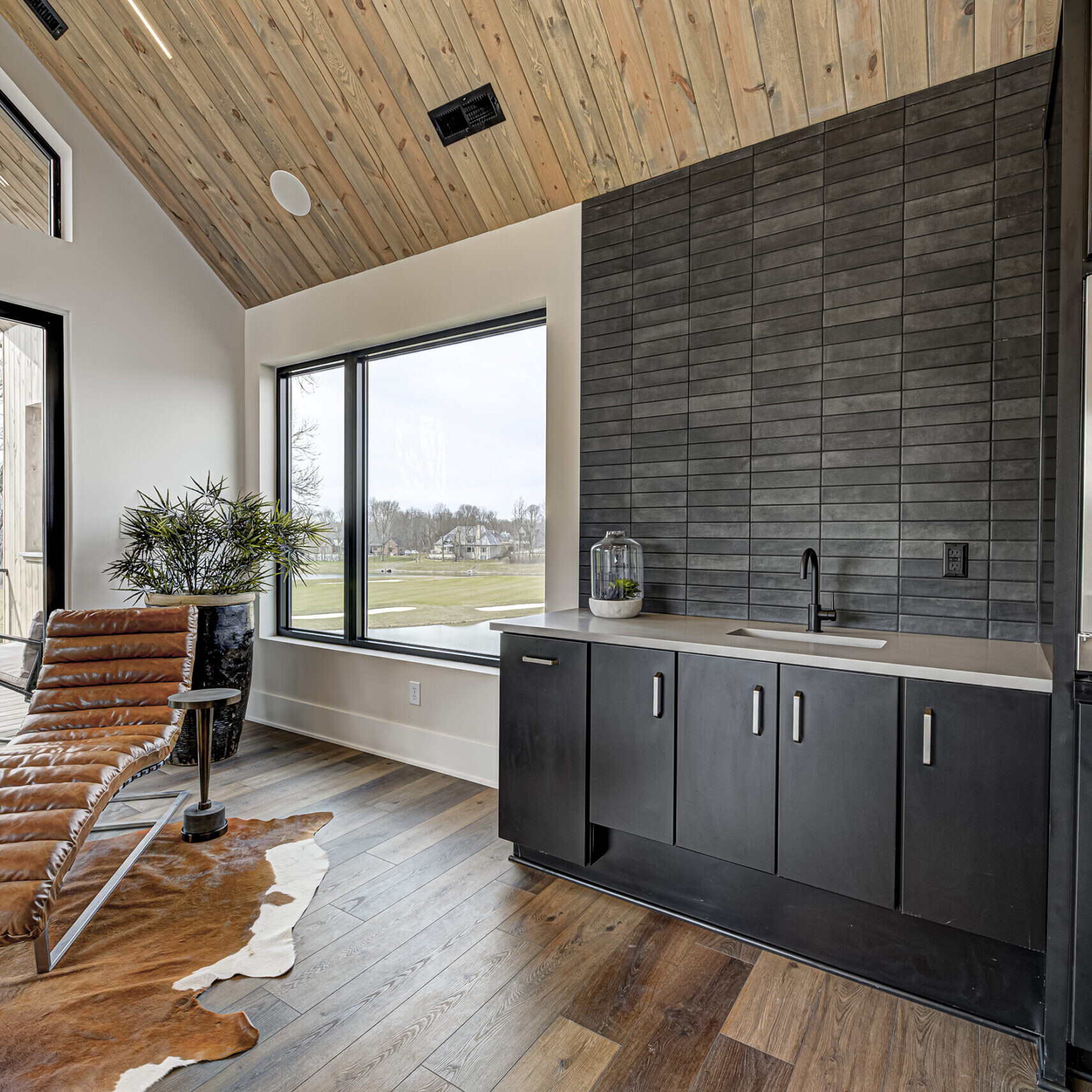 A kitchen with a large window and a cowhide chair.