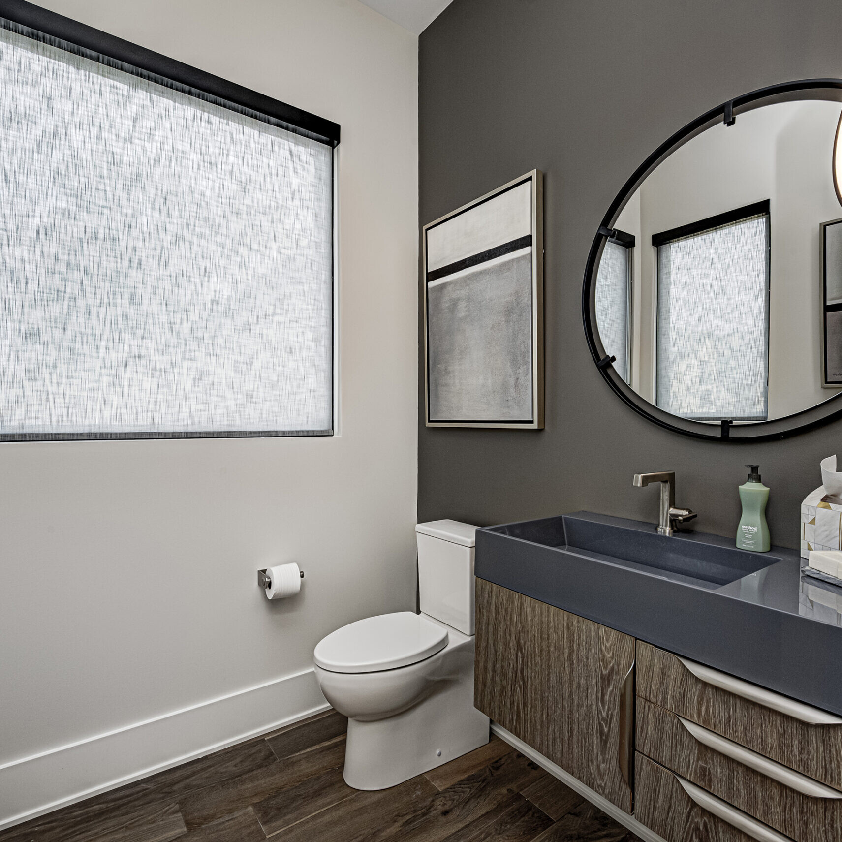 A bathroom with gray walls and a round window.