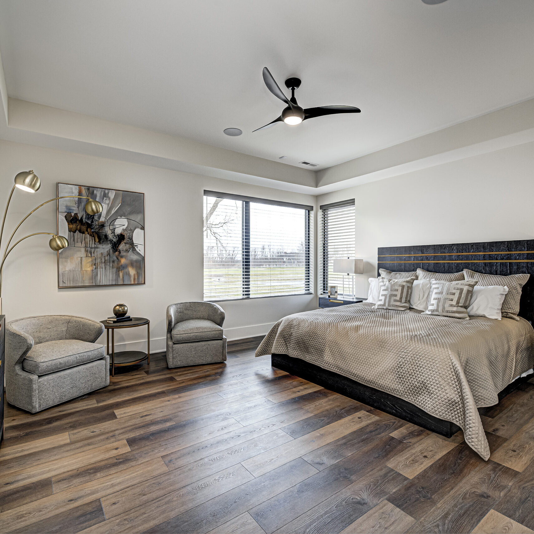 A bedroom with hardwood floors and a ceiling fan.