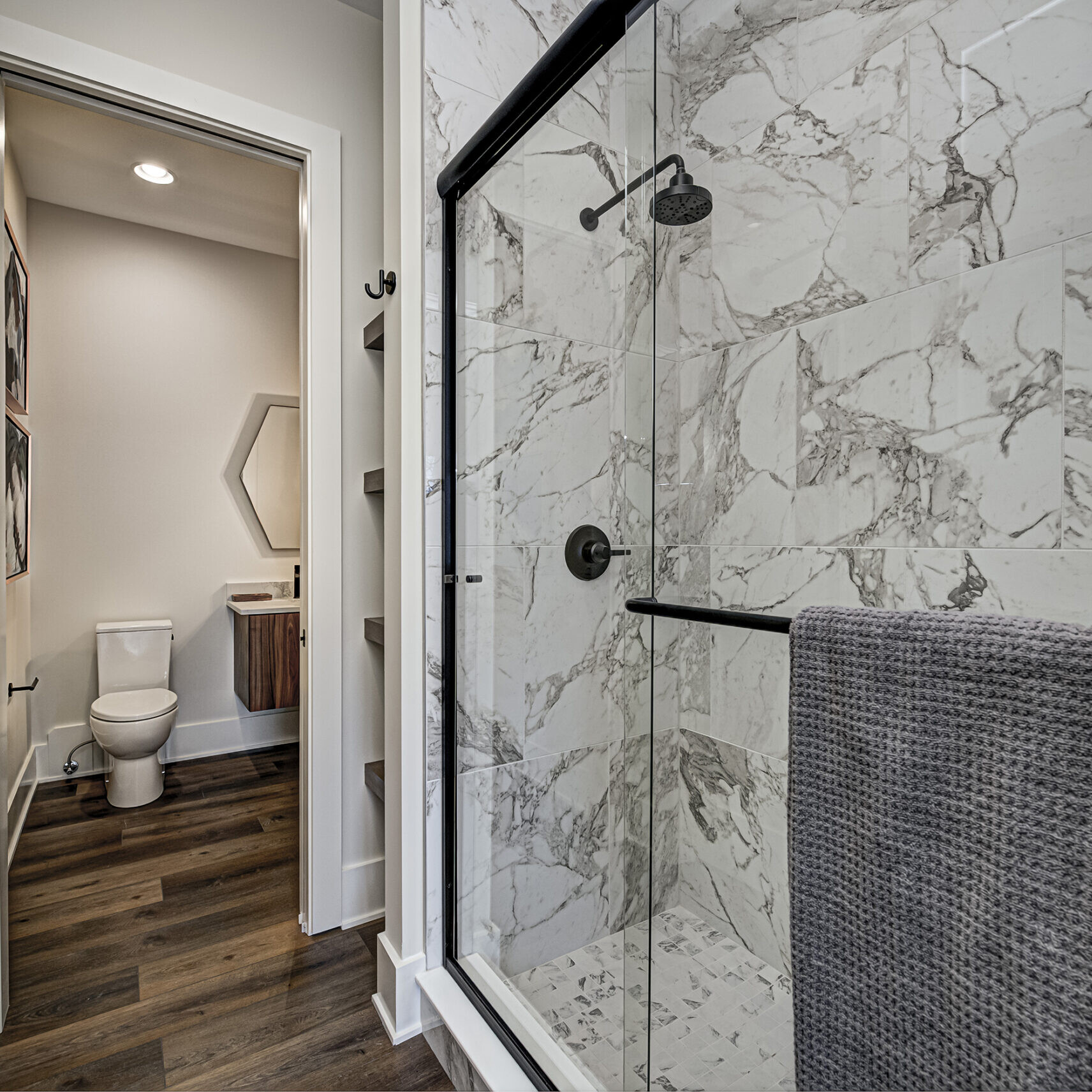 A bathroom with marble floors and a shower stall.