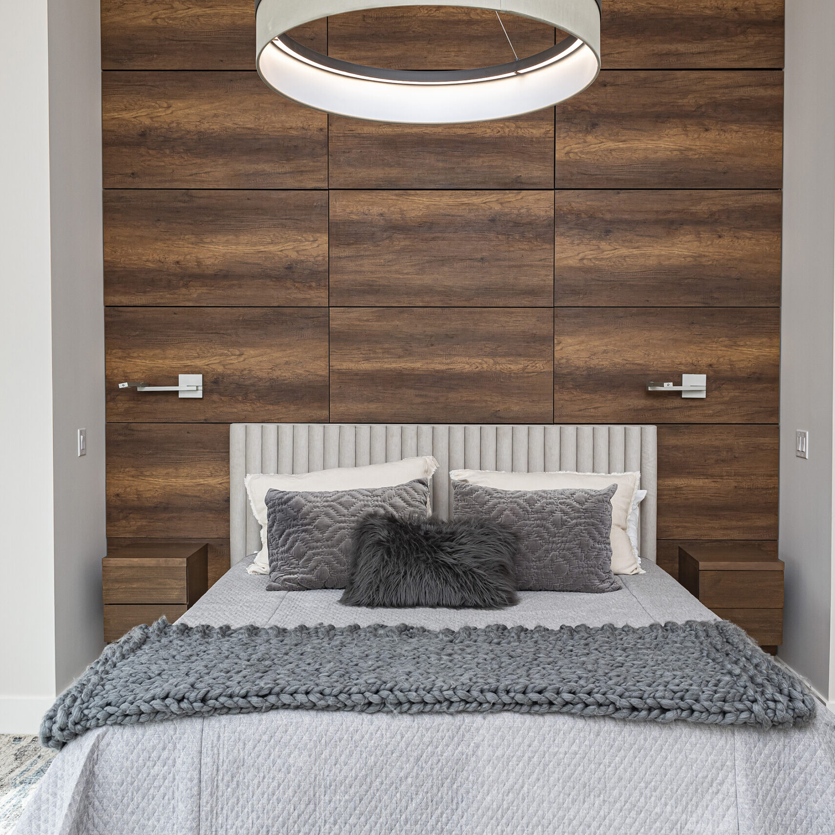 A bedroom with wood paneling and a light fixture.