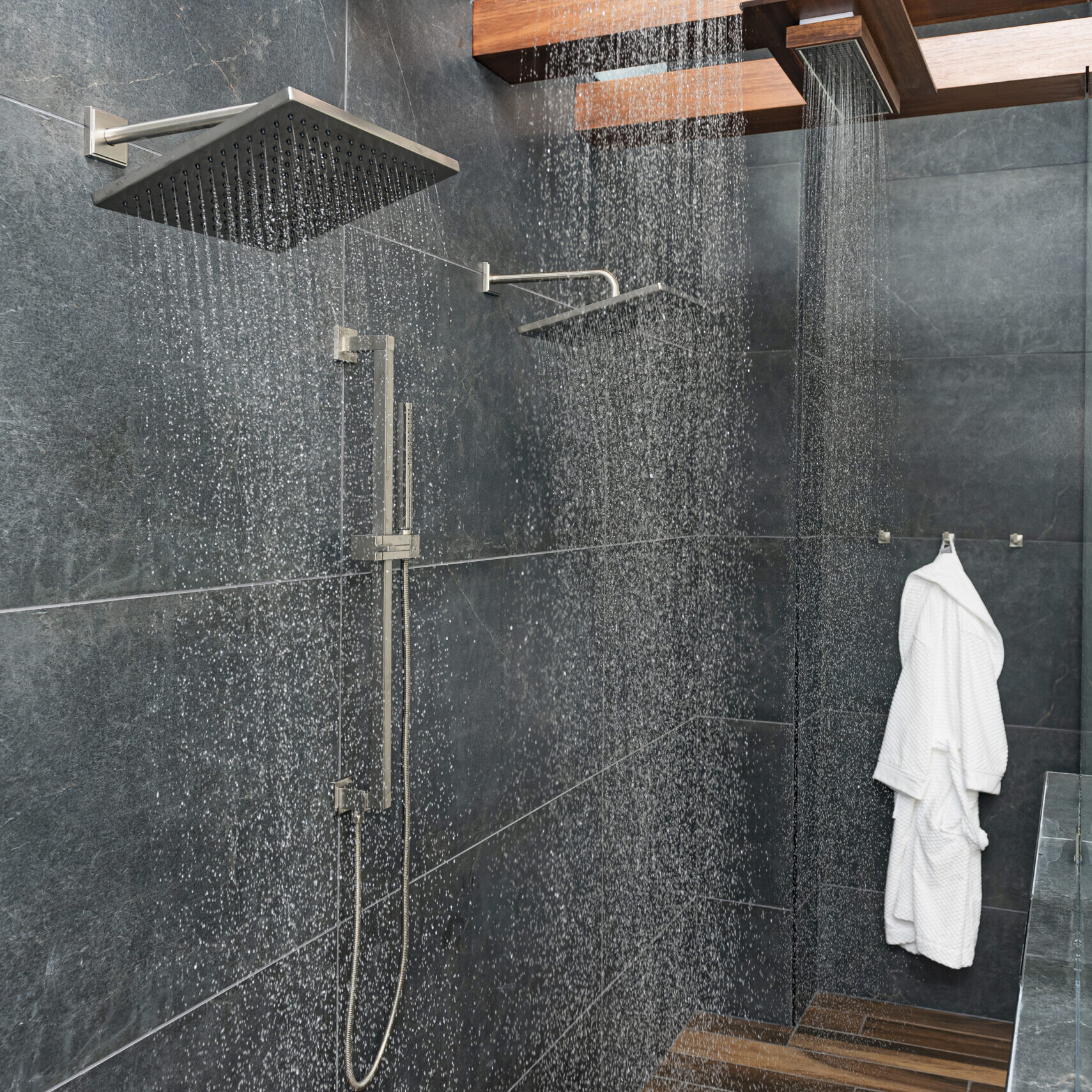 A bathroom with a shower head and a wooden floor.