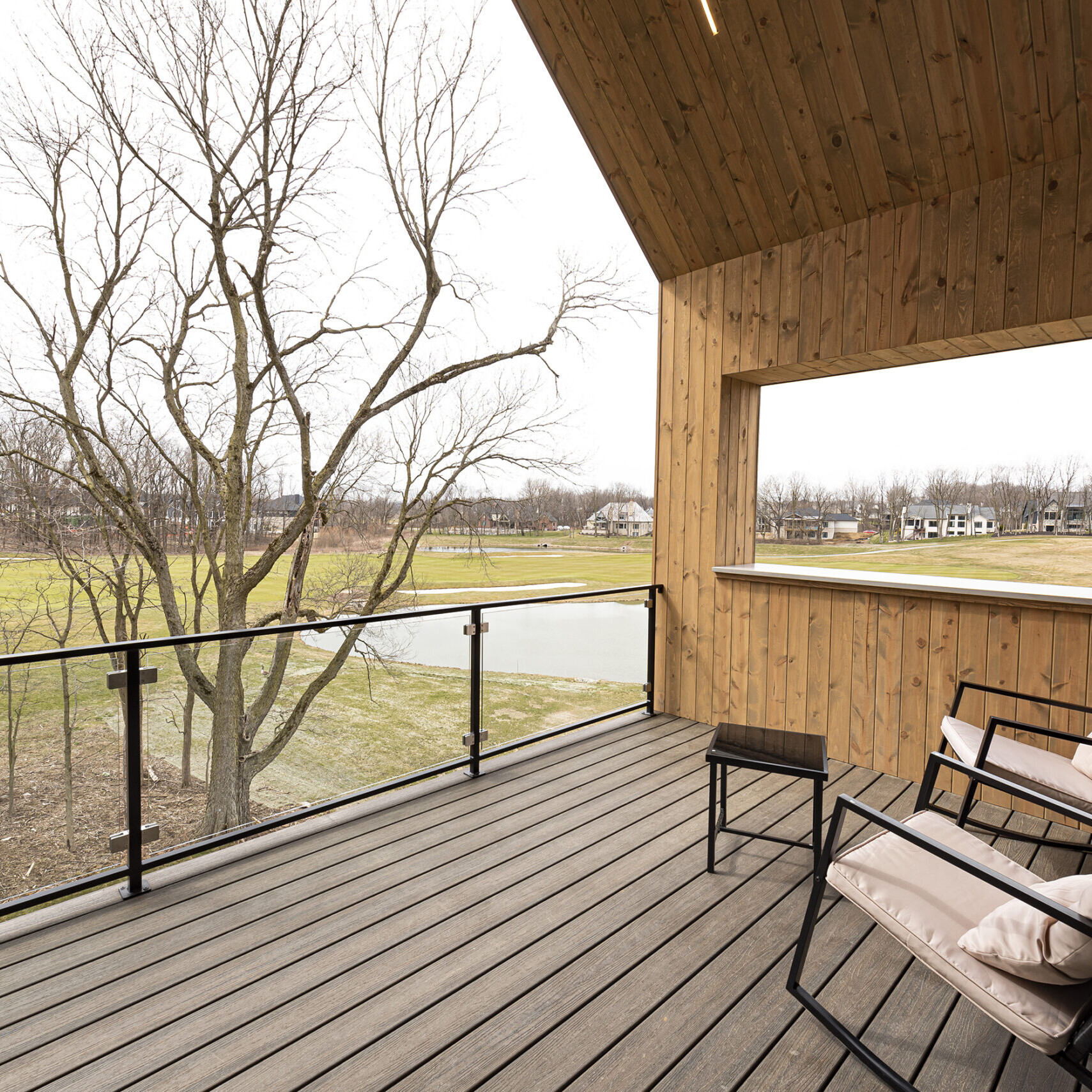 A wooden deck with chairs and a view of a lake.