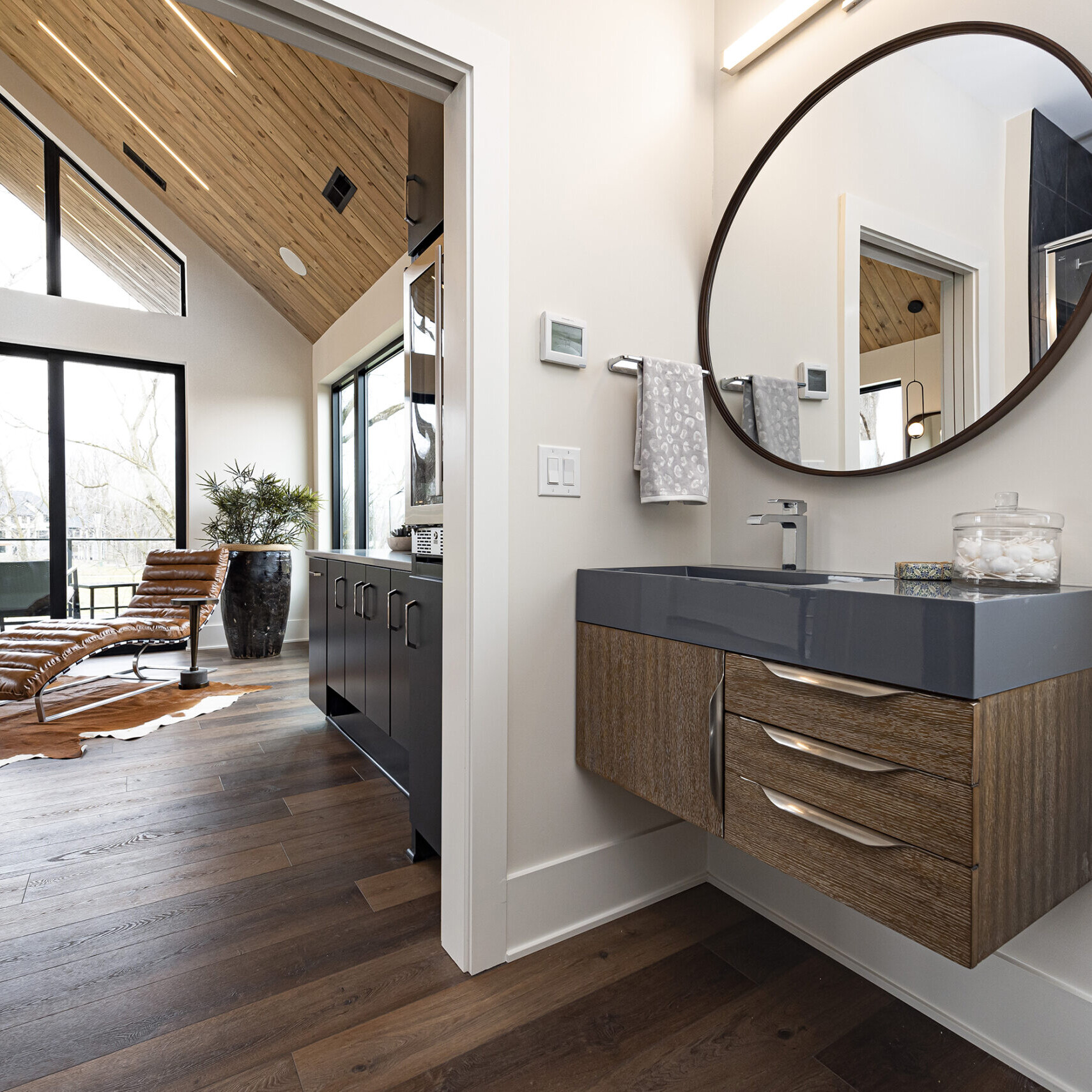 A bathroom with wood floors and a large mirror.