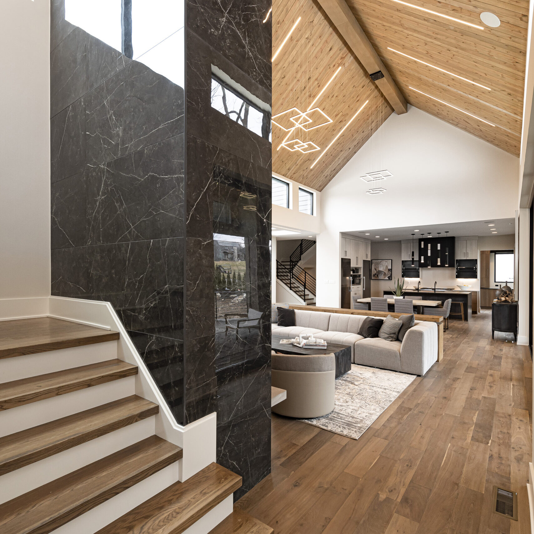 A modern living room with wood floors and stairs.