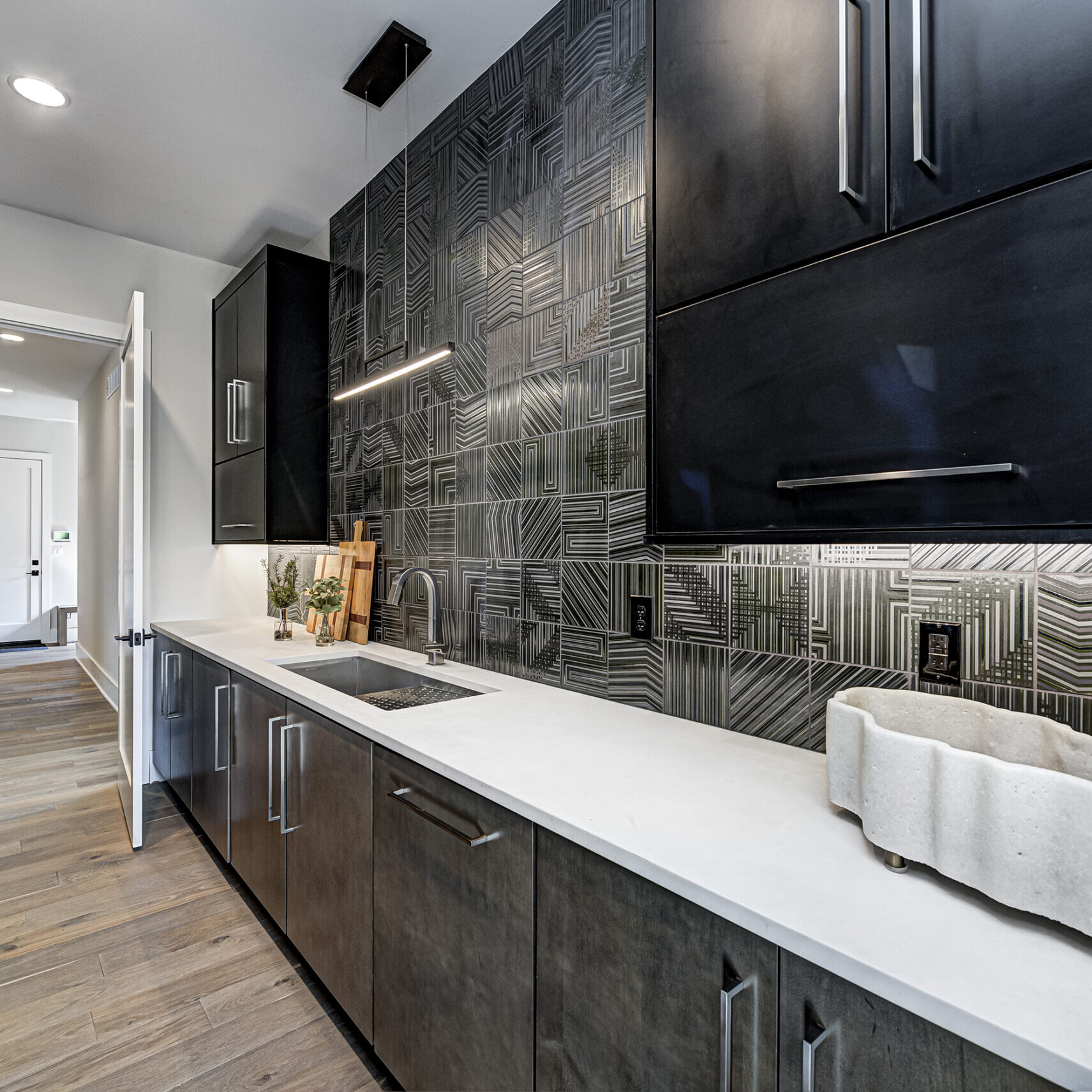 A kitchen with black cabinets and tiled walls.