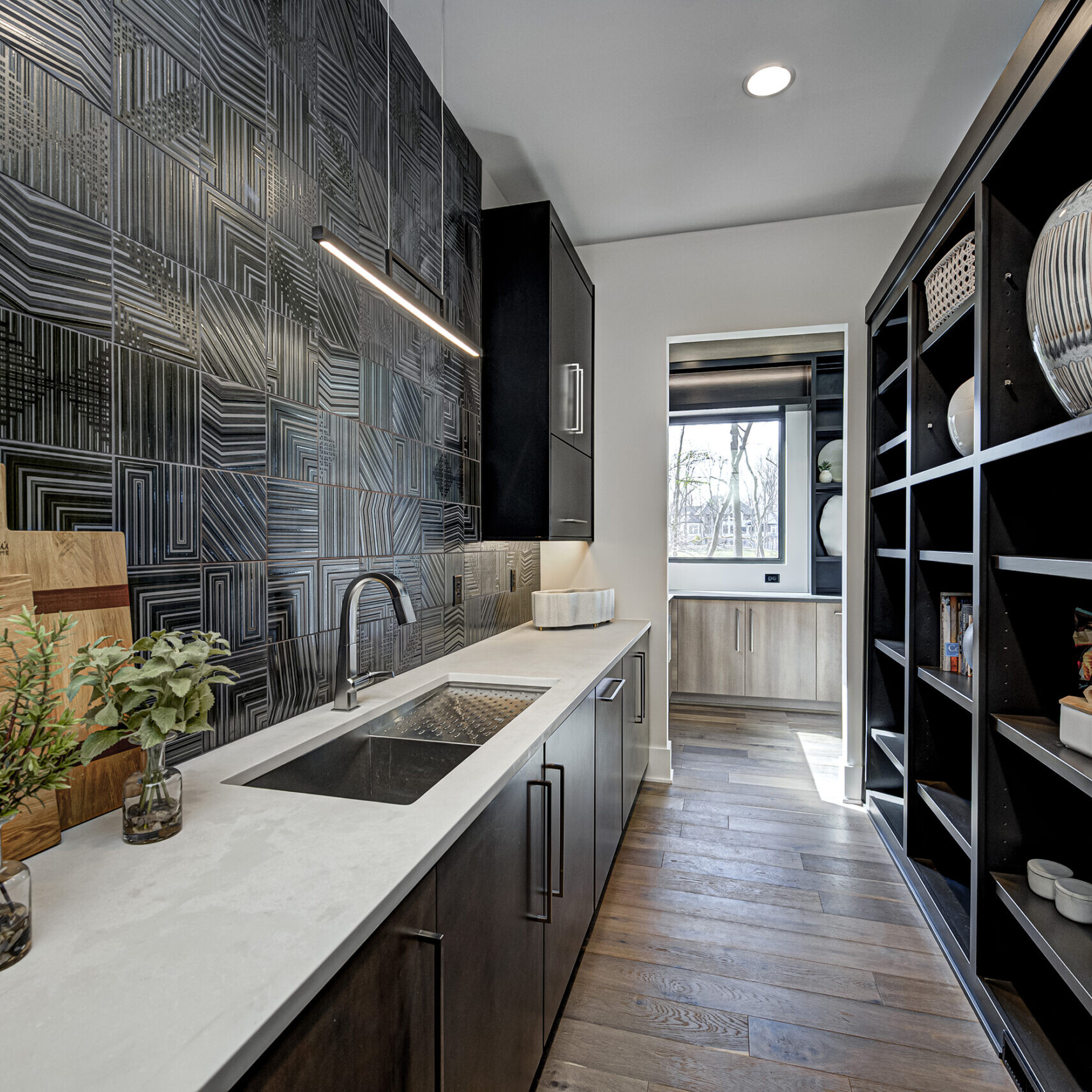 A kitchen with black and white tiled walls and a sink.