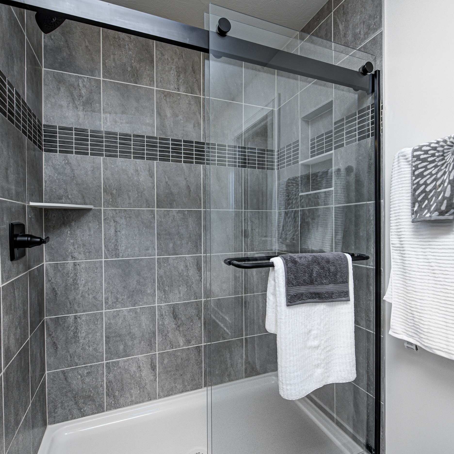 A bathroom with a glass shower door and towel rack.