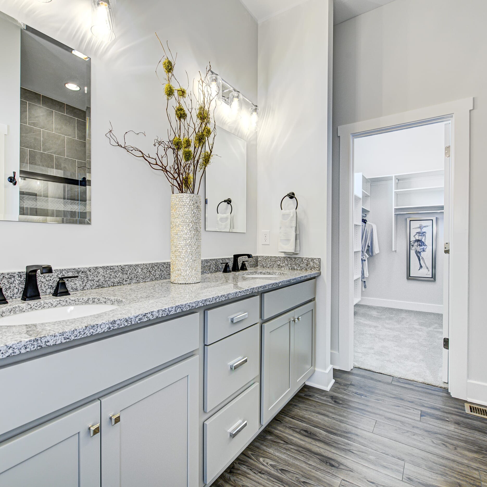 A bathroom with gray cabinets and granite counter tops.