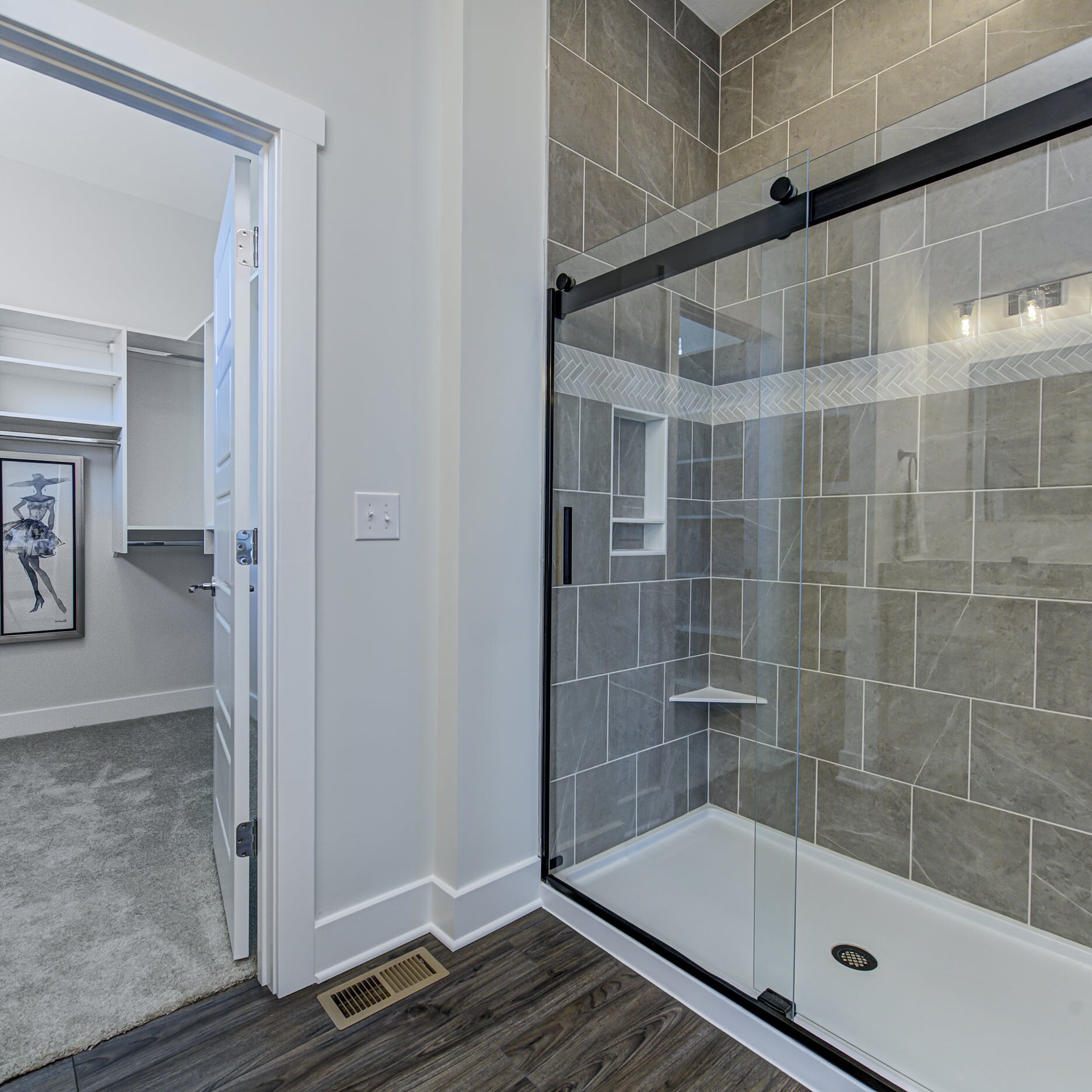 A bathroom with a glass shower door and a walk in closet.