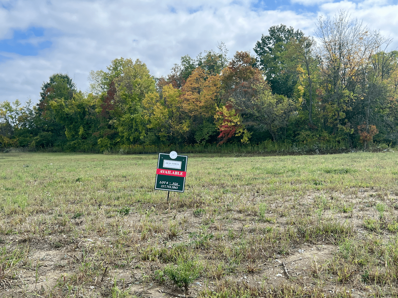 An empty field with a sign advertising new homes for sale in Carmel, Indiana.