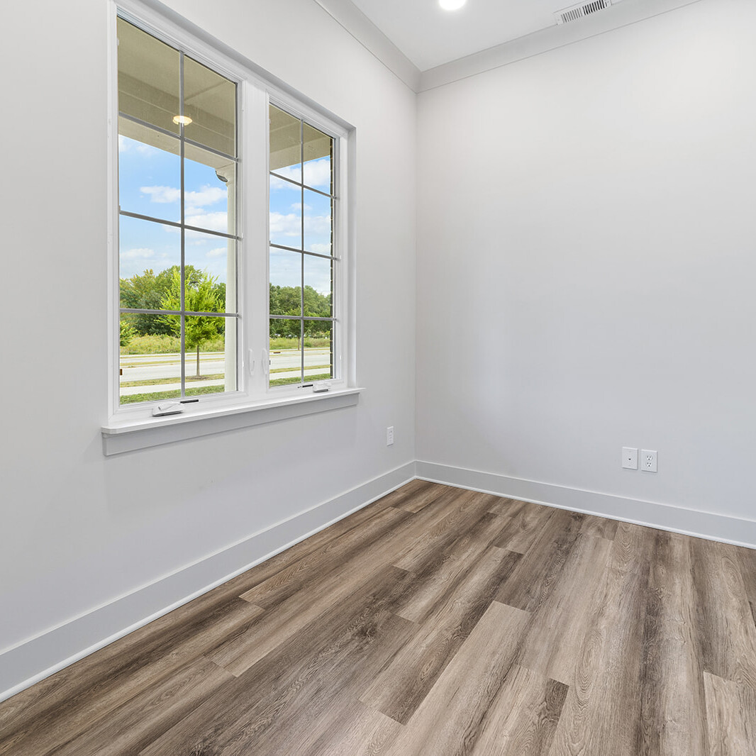 An empty room with wood floors and a window, perfect for custom home buyers in Indiana.