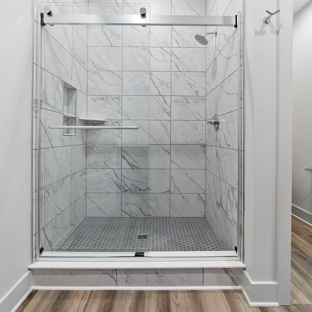 A bathroom with a glass shower stall and hardwood floors in a new home for sale in Carmel Indiana.