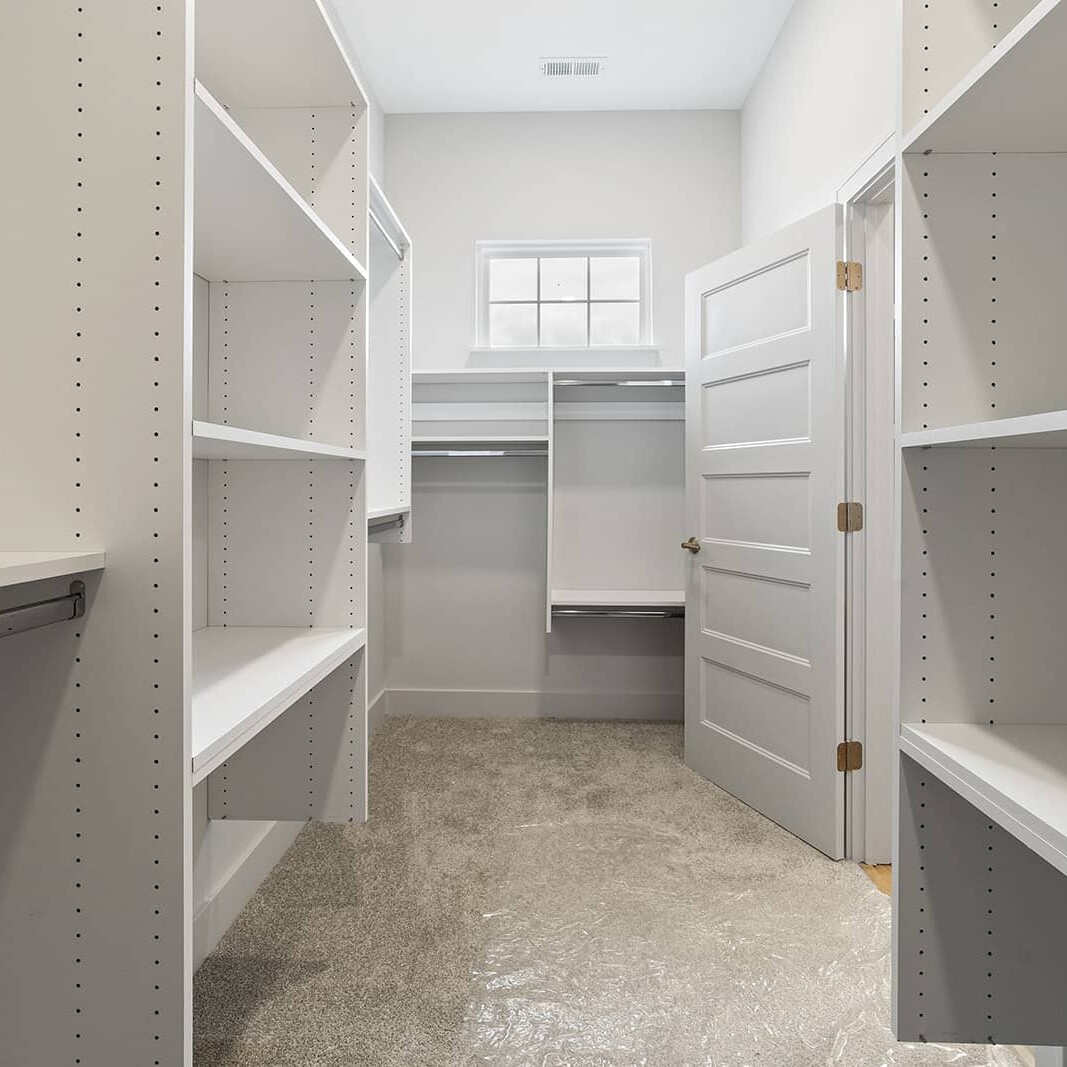 A walk in closet with shelves and a door, perfect for organizing your new luxury custom home in Carmel Indiana.