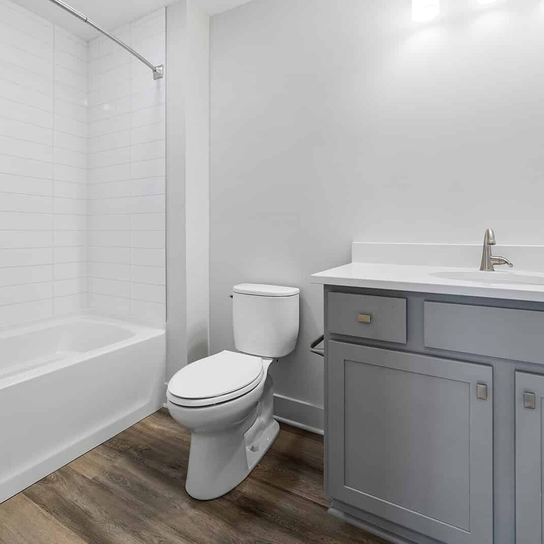 A bathroom with white walls and wood floors in a newly built home for sale in Carmel Indiana.
