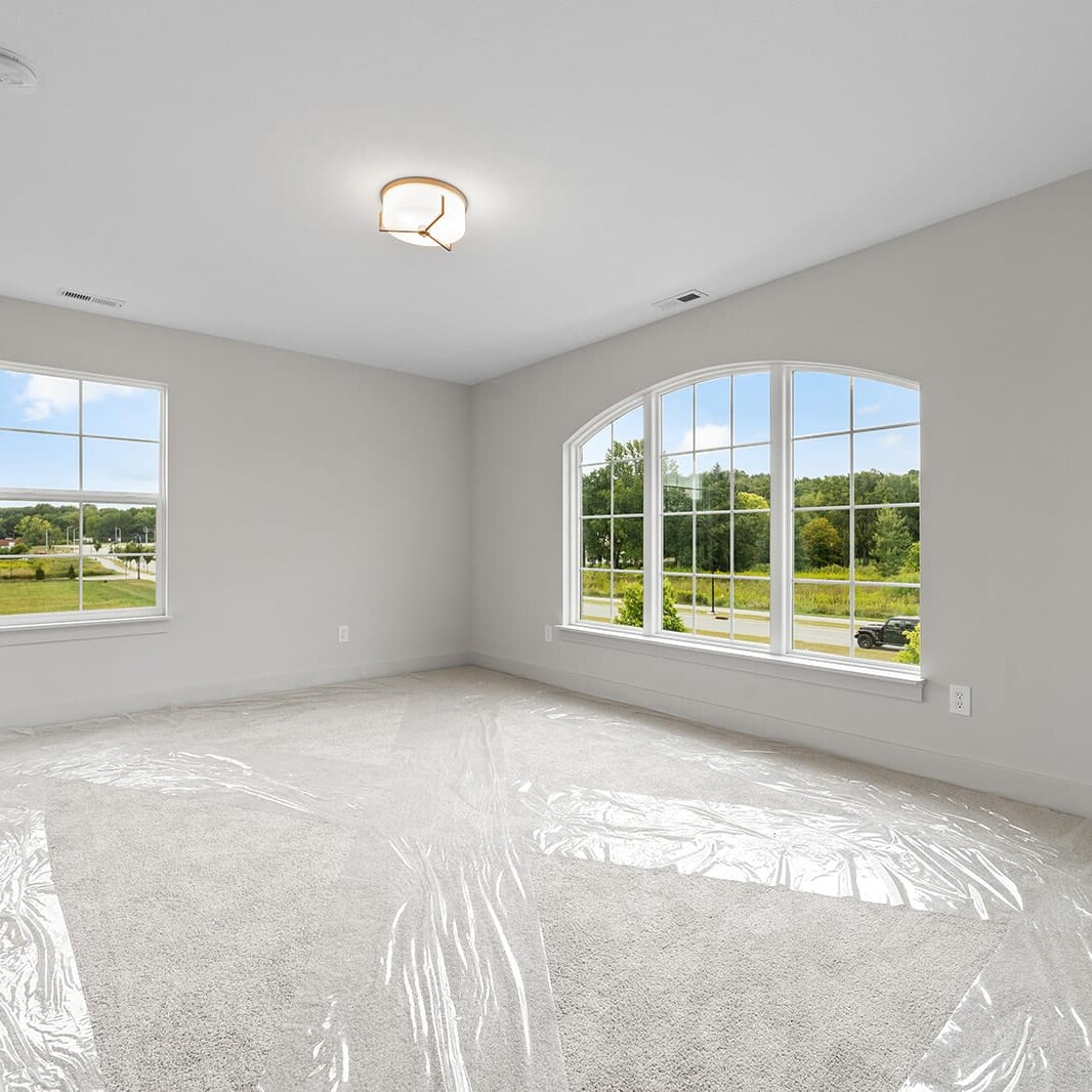 An empty room with white walls and a window in a custom home builder's showcase house for sale in Carmel, Indiana.