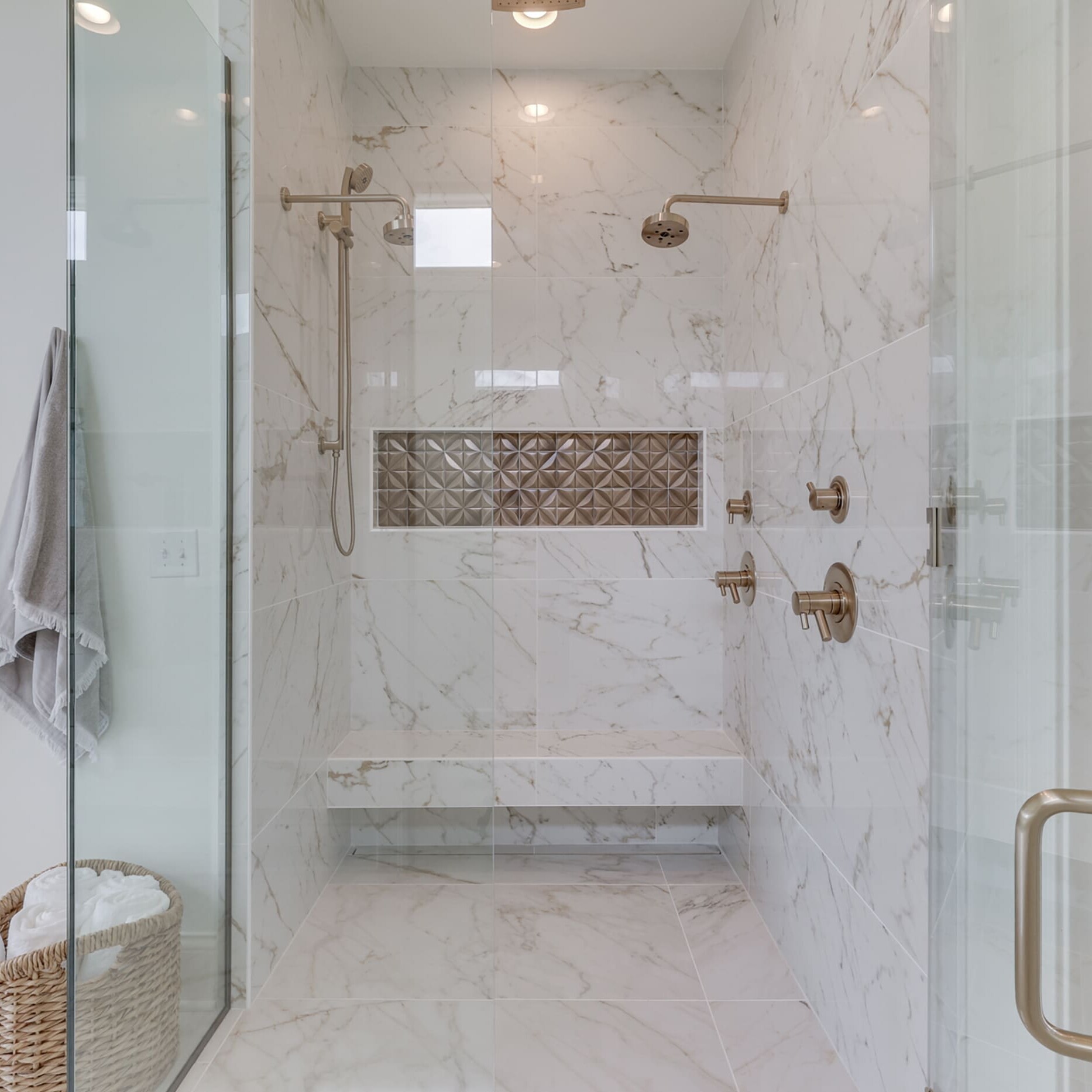 A bathroom with a glass shower stall and a bench.