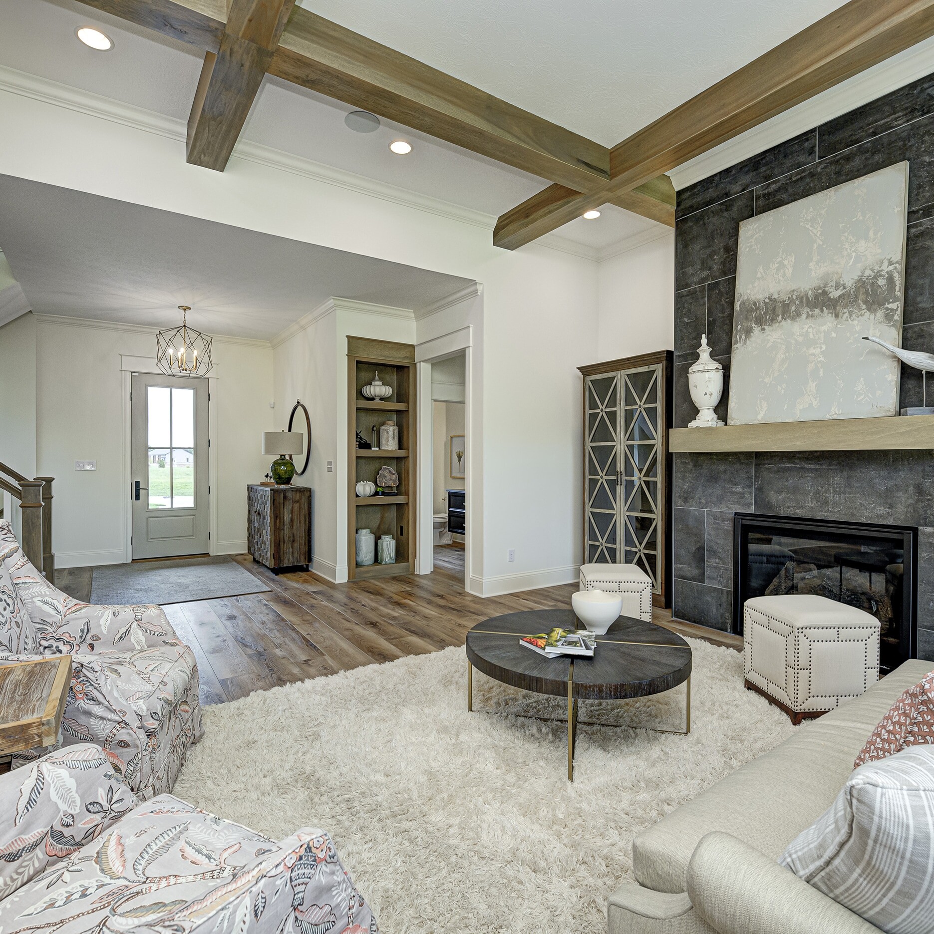 A living room with a stone fireplace and wood beams.